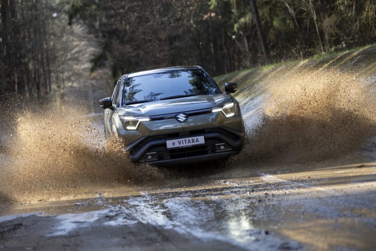 Ein Suzuki e VITARA fährt durch eine Pfütze.