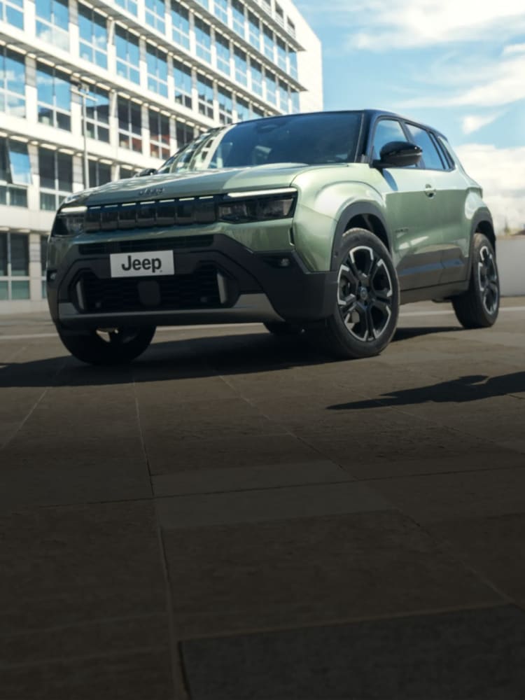 Grüner Jeep Avenger Elektro vor einem Gebäude.