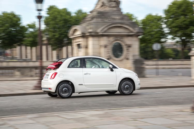Ein weißes Fiat 500 Cabrio fährt auf der Straße.