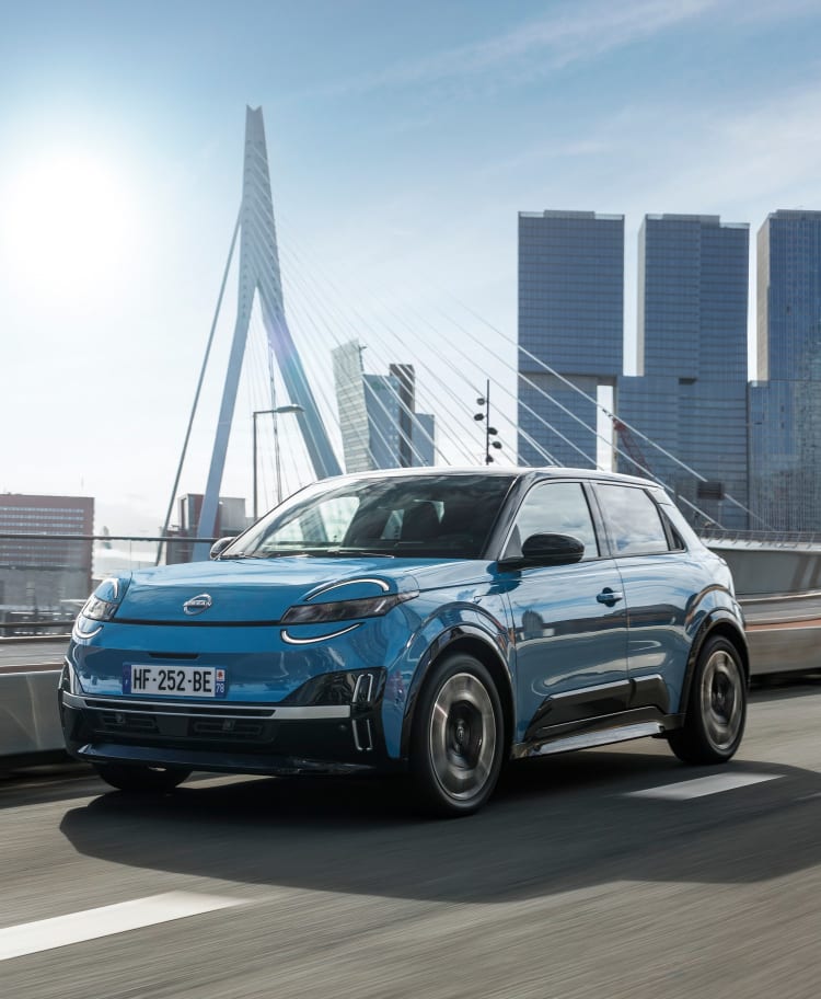 Blauer Nissan Micra auf einer Stadtbrücke.