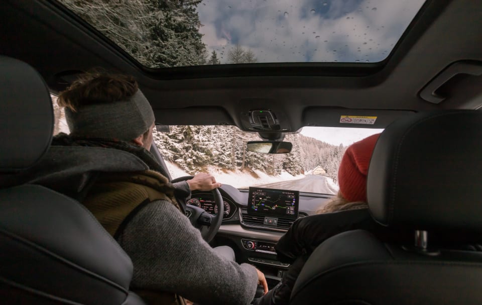 Ein Paar sitzt in ihrem Leasingfahrzeug und fährt durch den Schnee. 