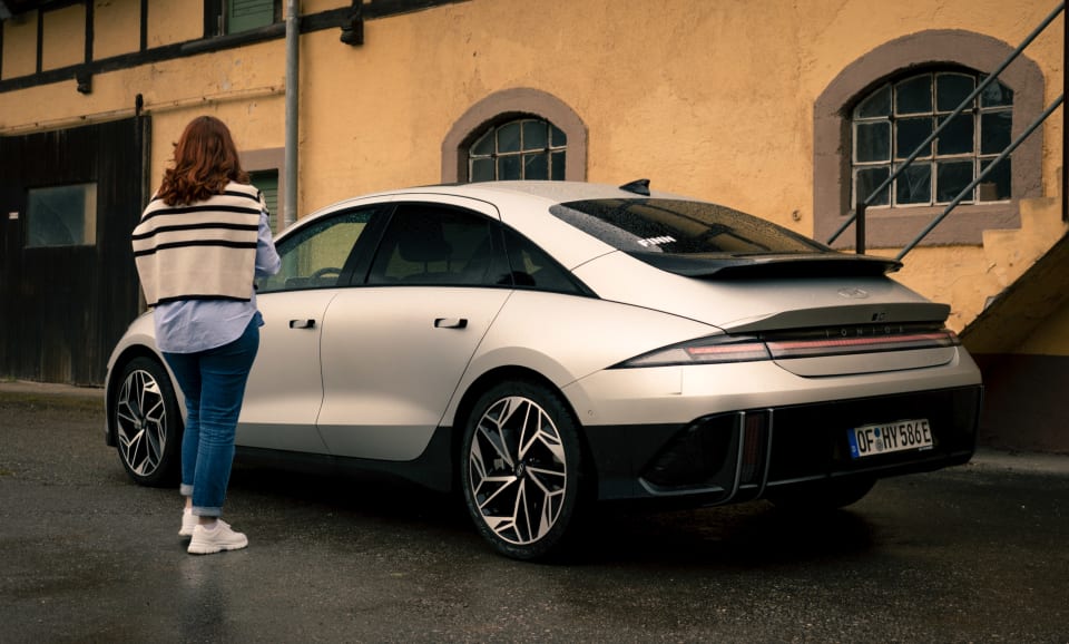 Eine Frau läuft auf einen Hyundai IONIQ 6 zu.