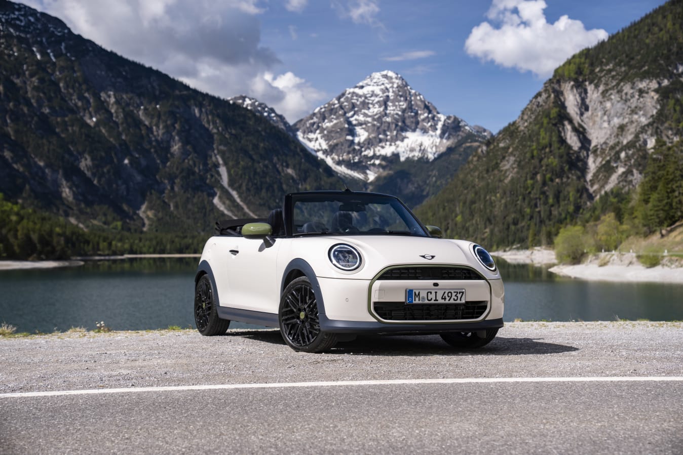 Ein weißes MINI Cooper Cabrio vor einer Bergkulisse.