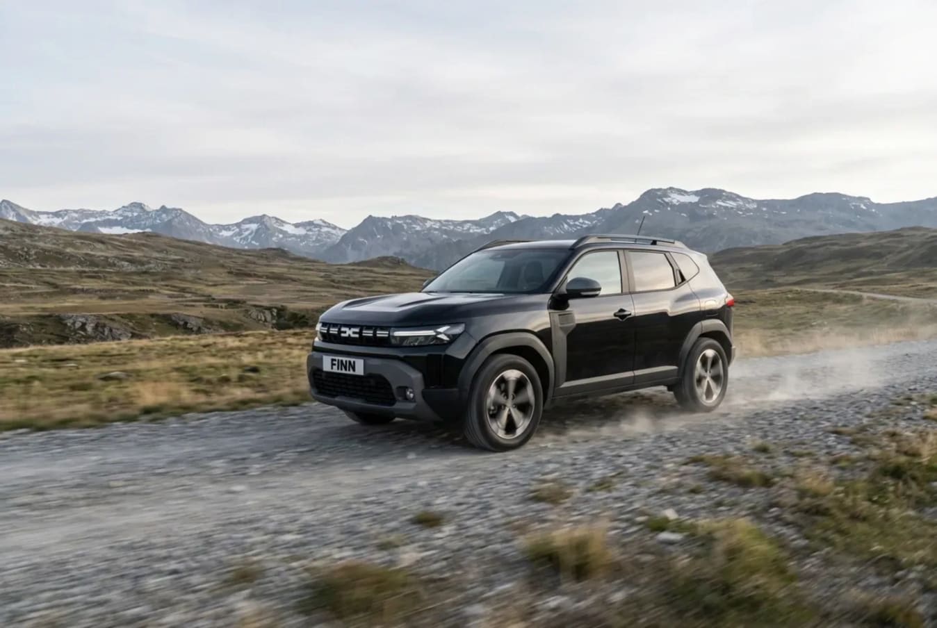 Ein Paar sitzt in einem Dacia von FINN und lacht.