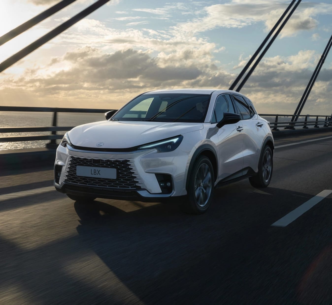 Ein weißer Lexus LBX fährt über eine Brücke.