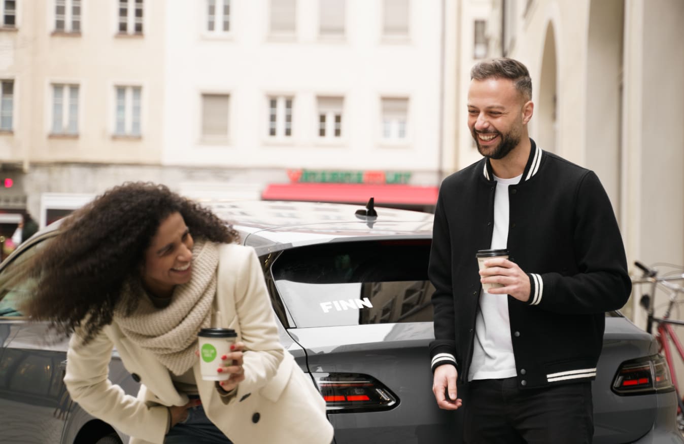 Ein Paar steht vor einem FINN Auto.