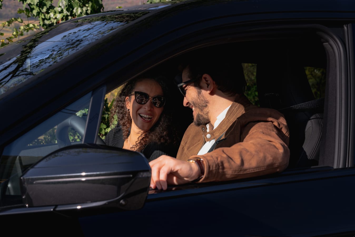 Ein Mann und eine Frau sitzen in einem FINN Auto und lächeln.