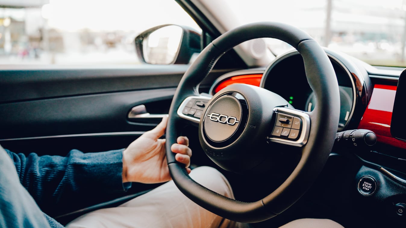 Ein Mann lenkt einen Fiat 600.