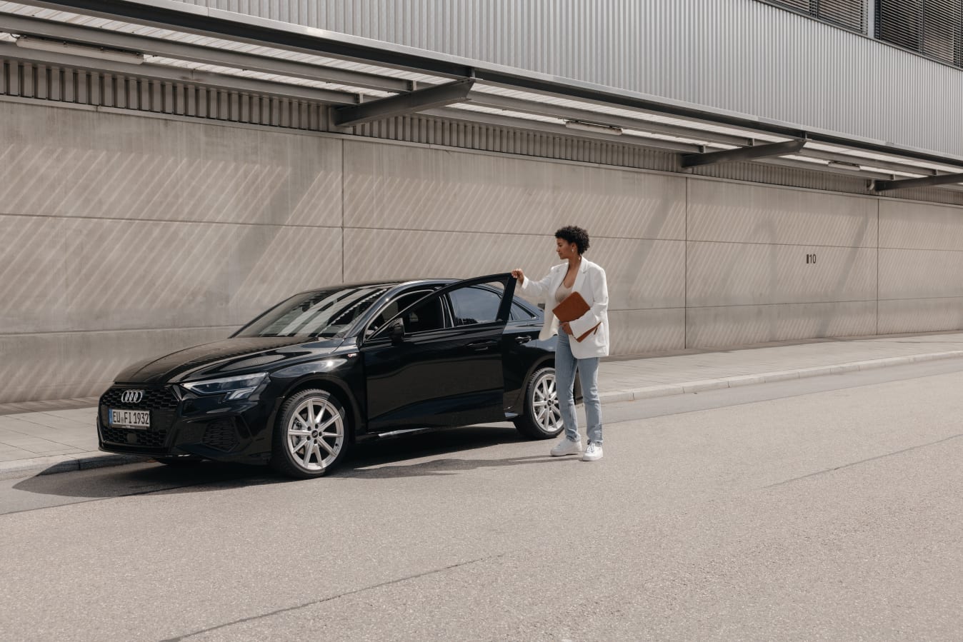 Eine Frau hält die offene Tür eines FINN Autos fest.
