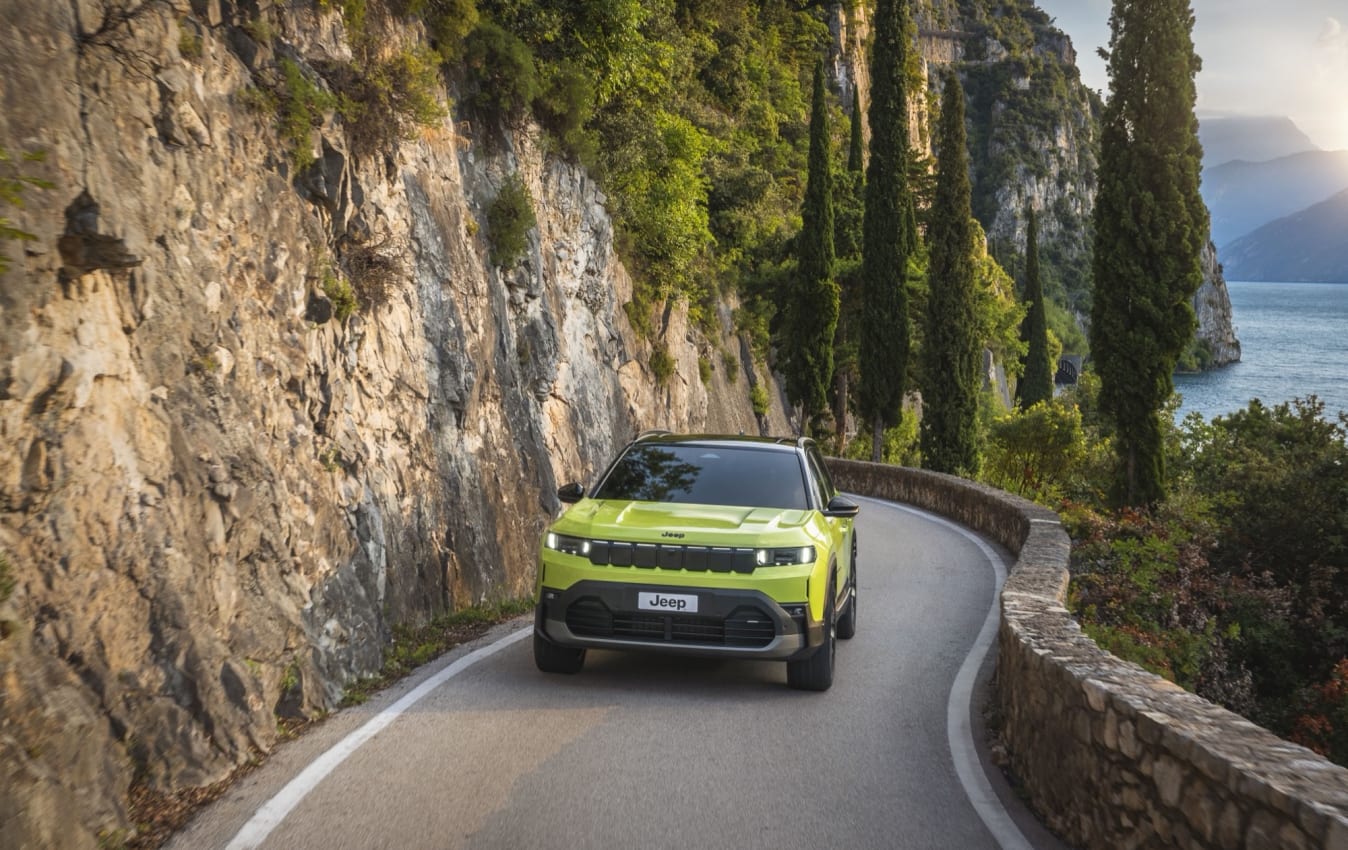 Ein grüner Jeep Avenger fährt auf einer Küstenstraße.