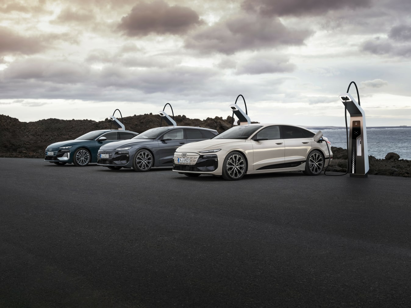 Drei Audi e-tron Modelle, die an Ladesäulen stehen.