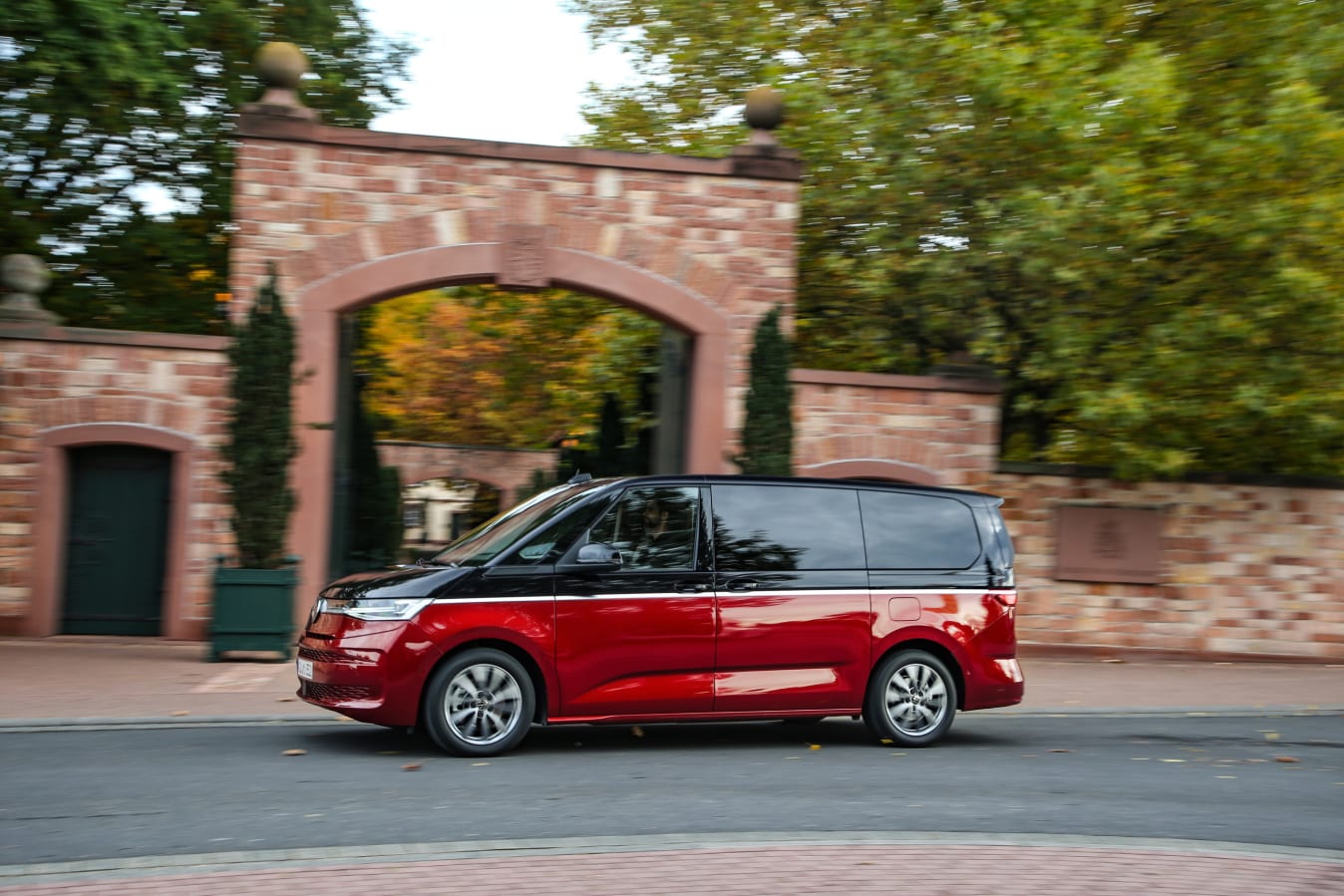 Ein roter VW Multivan fährt durch ein Torbogen-Tor.