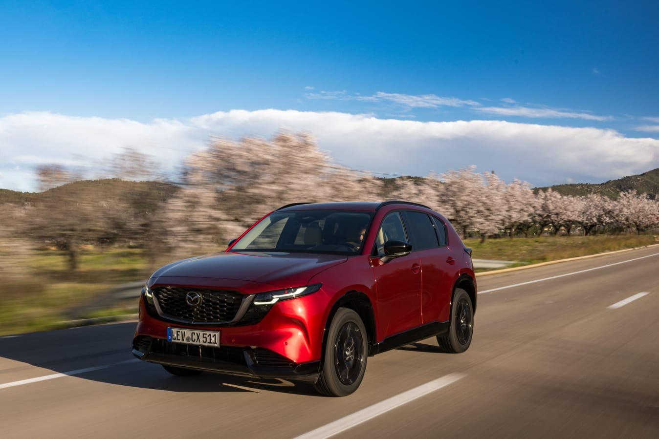 Ein roter Mazda CX-5 fährt auf einer Landstraße.