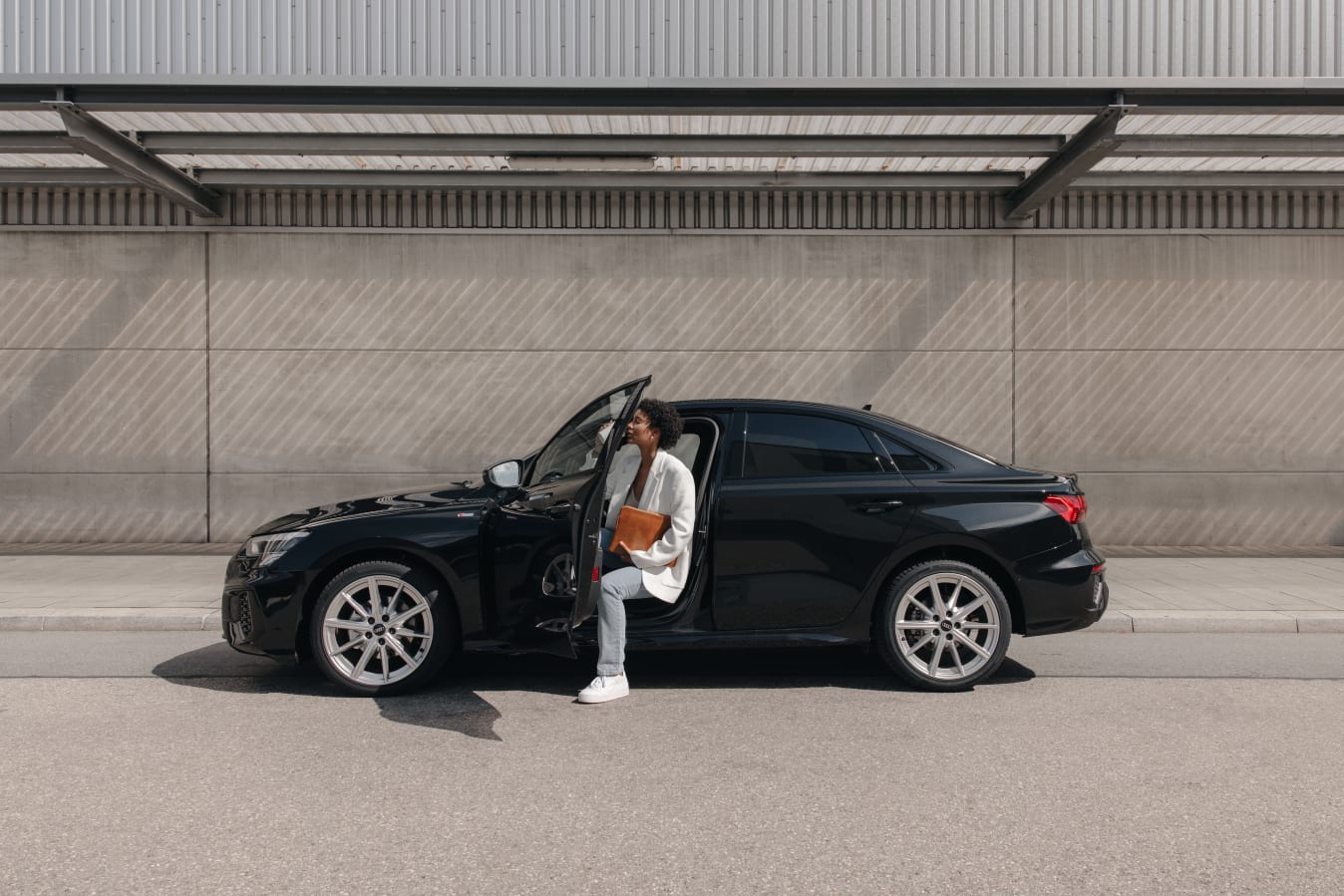 Frau steigt mit Fahrtenbuch in der Hand aus Audi A3 von FINN aus.