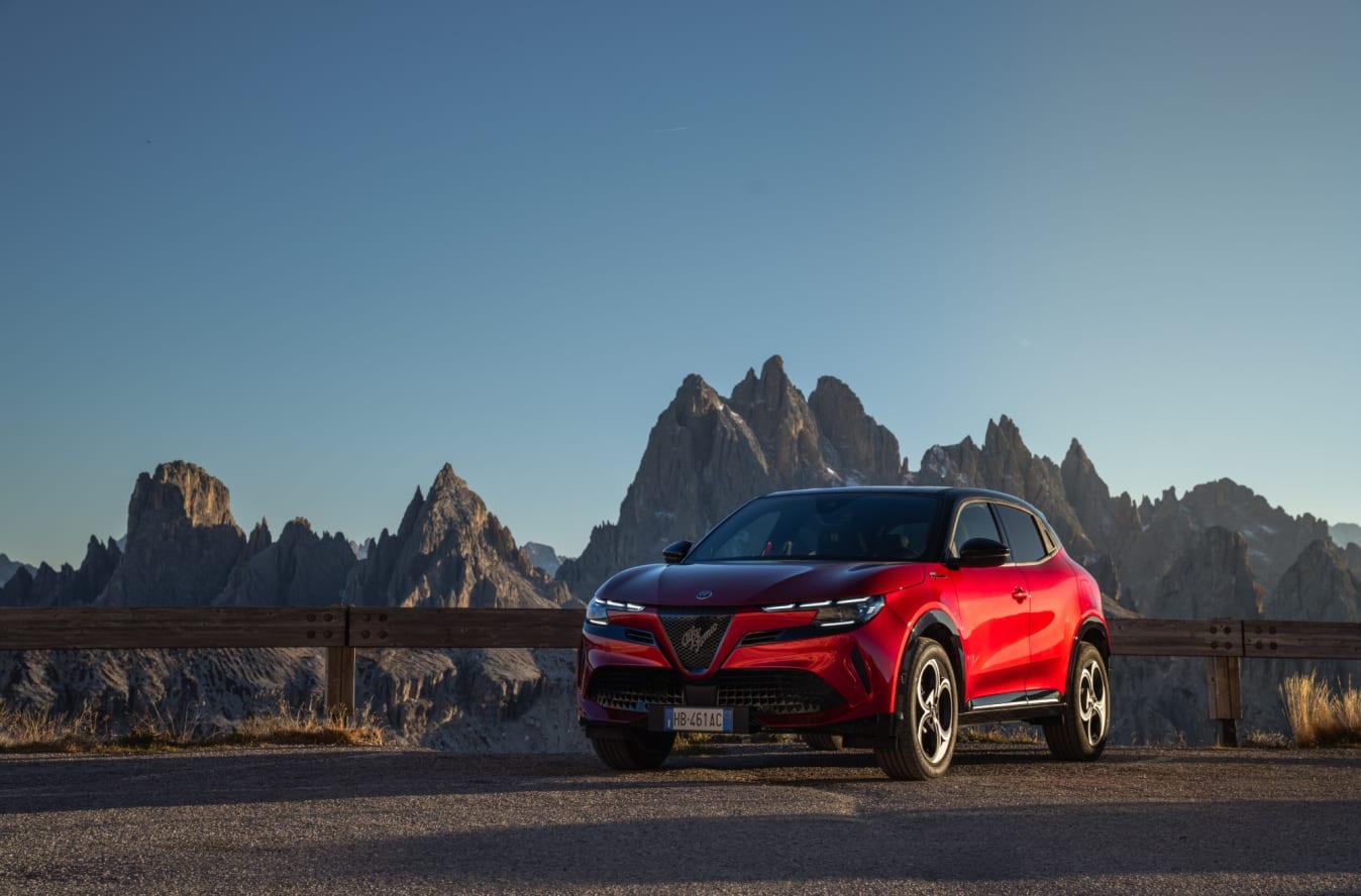 Ein roter Alfa Romeo Junior steht auf einem Alpenpass.