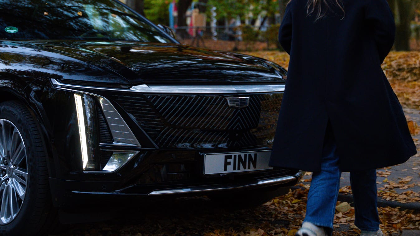 Eine Frau läuft vor einem Cadillac Lyric vorbei.