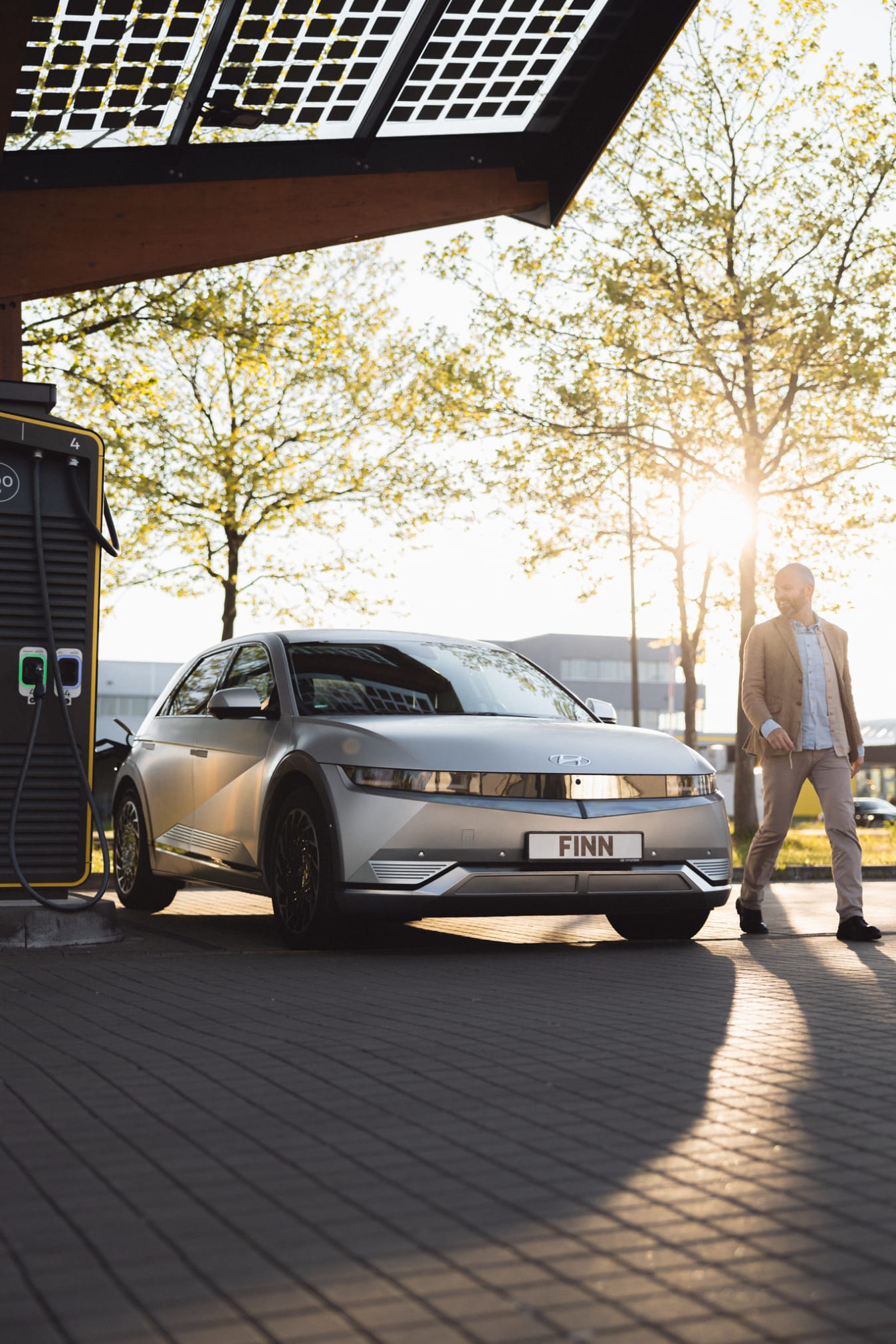 Ein Mann geht von einer Ladesäuke weg, an der ein IONIQ 5 geladen wird.
