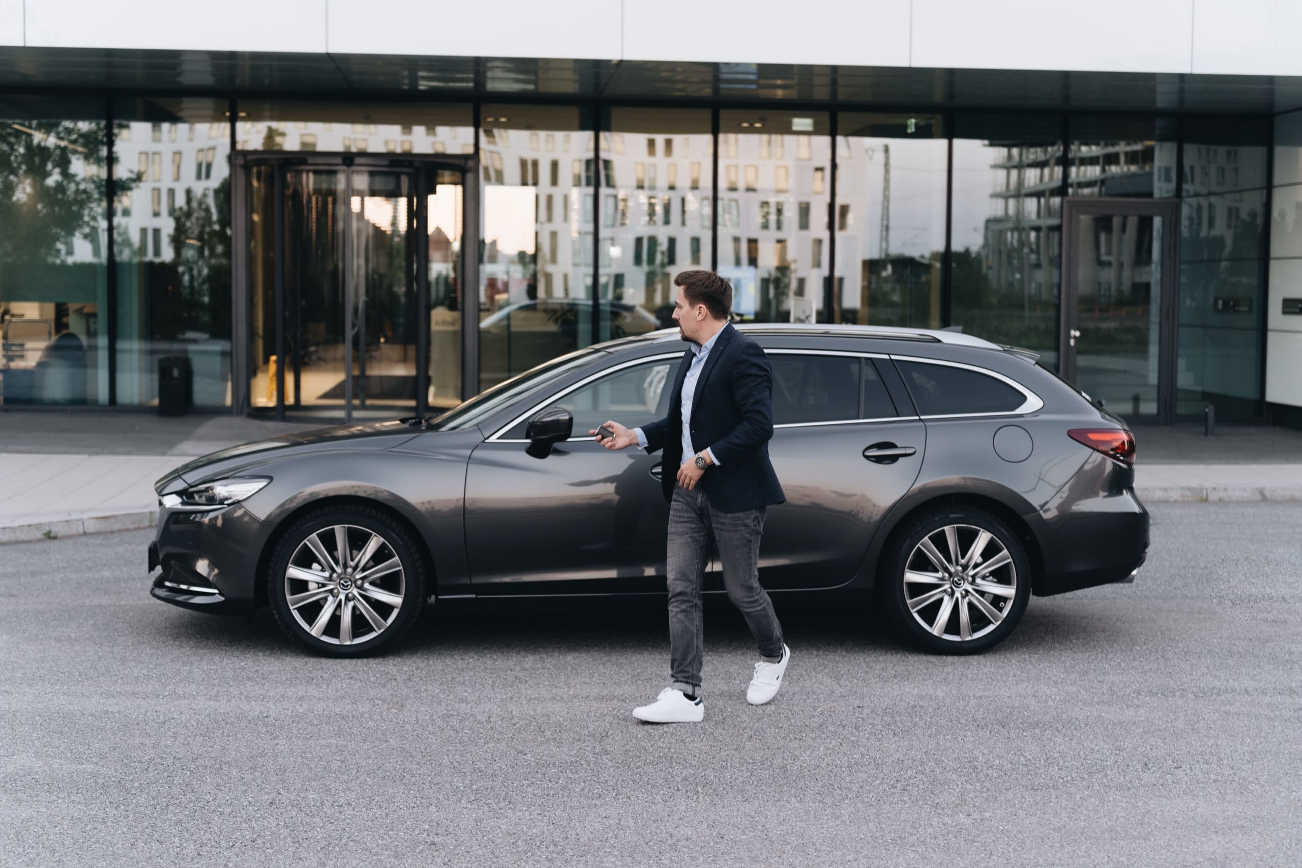Ein Mann schließt einen Mazda 6 Kombi von FINN ab.