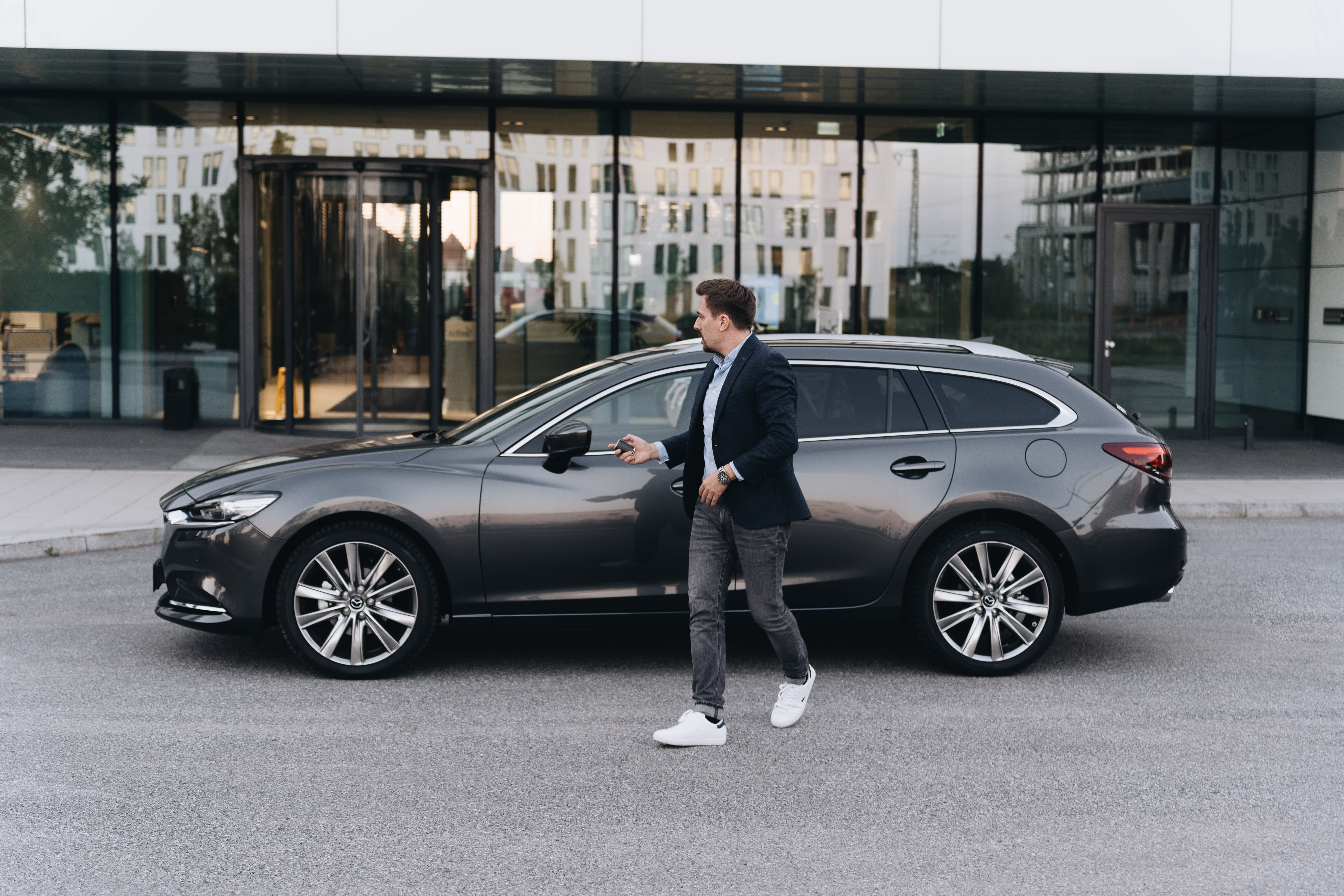 Ein Mann schließt einen Mazda 6 Kombi von FINN ab.