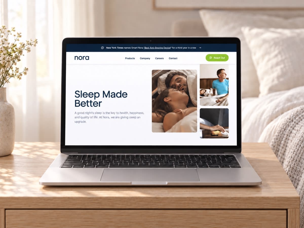 Smart Nora’s website on a laptop on a pale oak console in a softly lit bedroom