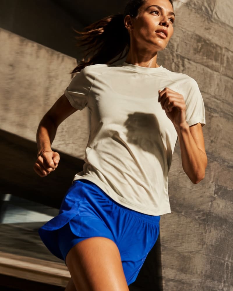 Runner in cobalt shorts moving through a sunlit concrete setting