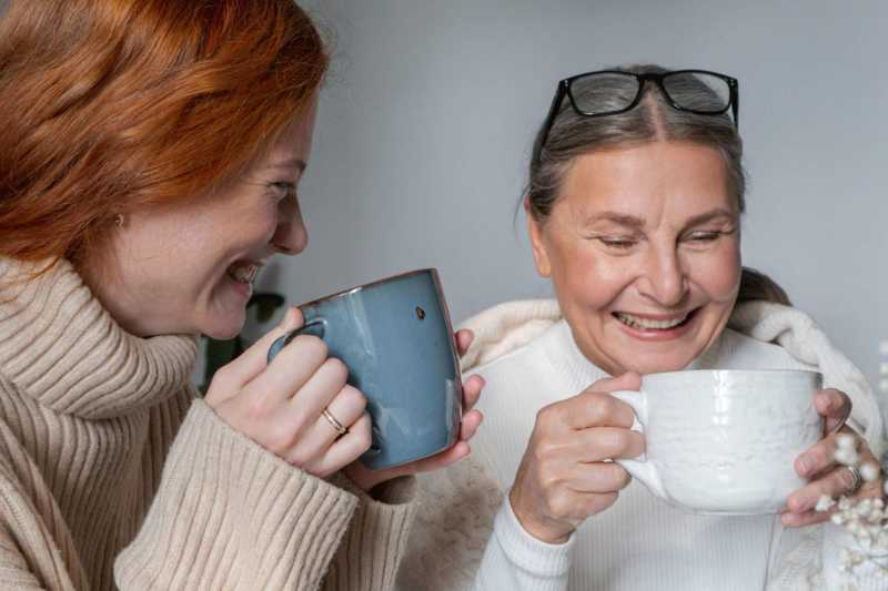 Two people smiling and drinking from mugs