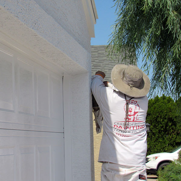 One of our painters covers a light fixture in a tarp to protect it during the prep work and painting process.