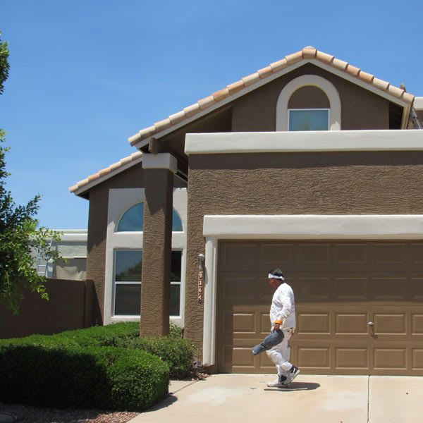A Crash of Rhinos painter walks in front of a freshly painted home here in Phoenix, inspecting his work as part of our quality assurance process.