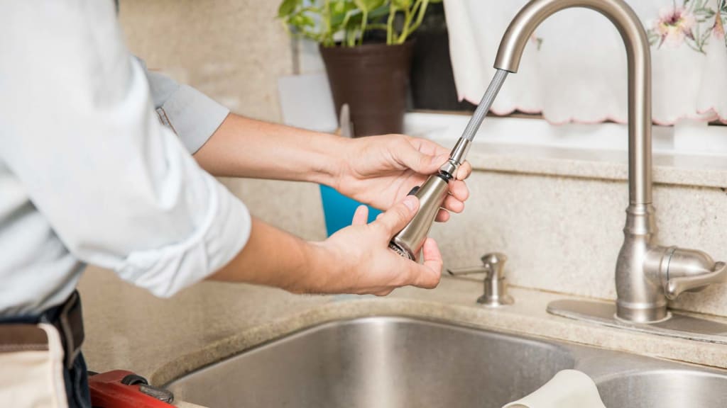 A King plumber attaches a spray nozzle to a kitchen sink spout as part our plumbing installation service.