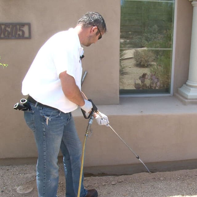A KY-KO termite treatment specialist here in Scottsdale, AZ applies termiticide to a trench.