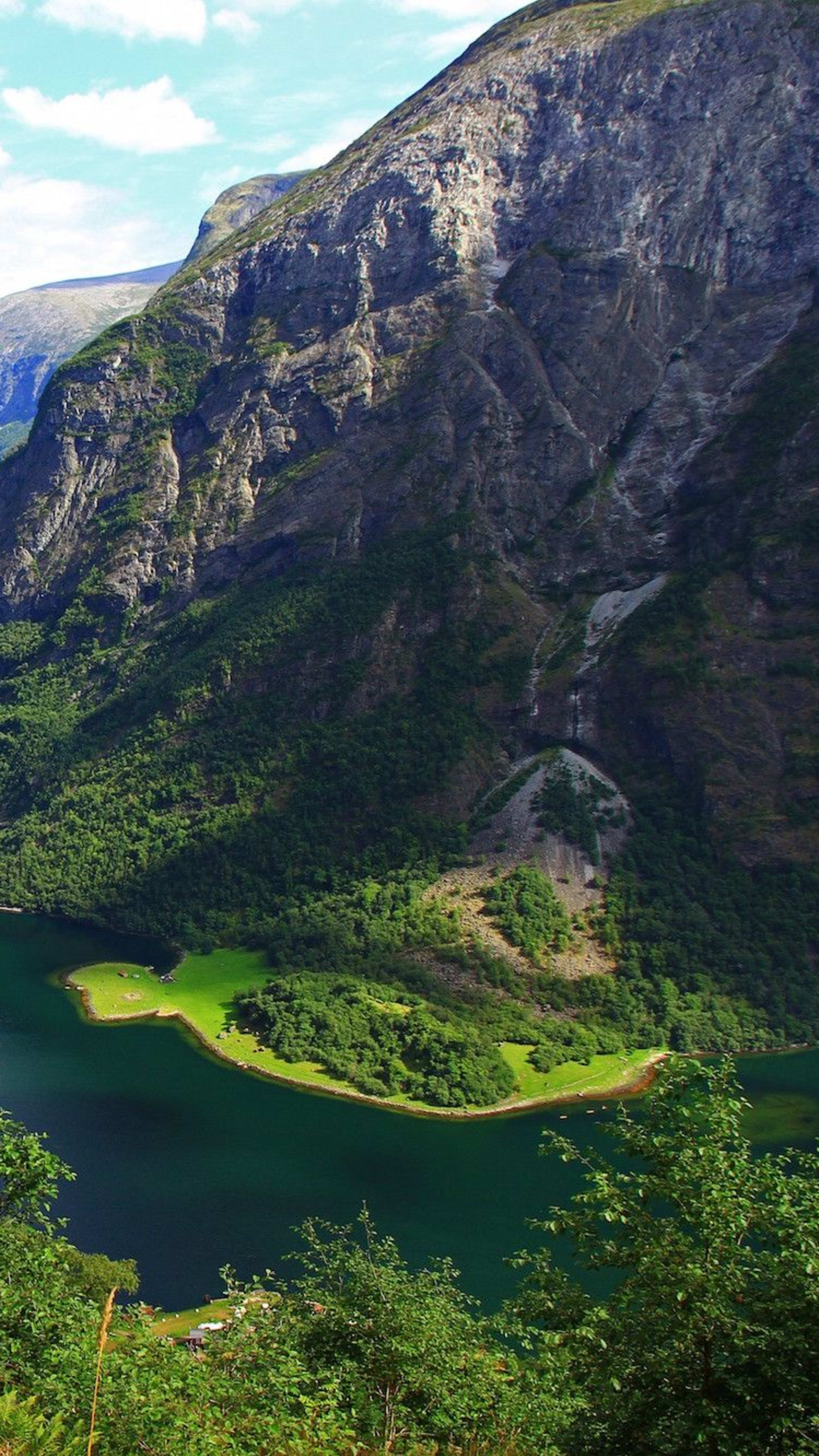 Nærøyfjorden slynger seg mellom grønne fjell, båt på blått vann.