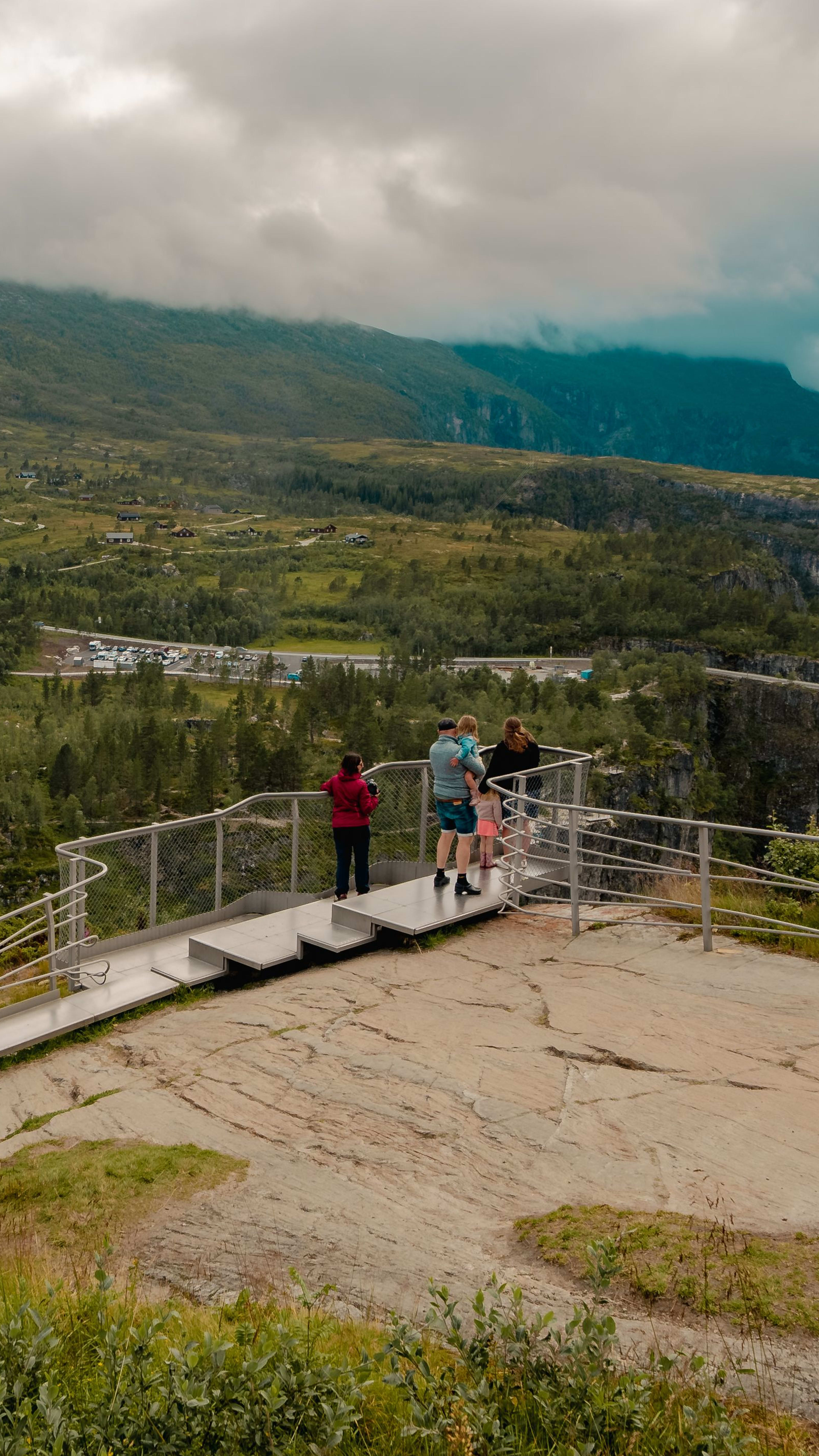 Besucher genießen am Aussichtspunkt Panoramablick auf grüne Hügel und Wasserfall.