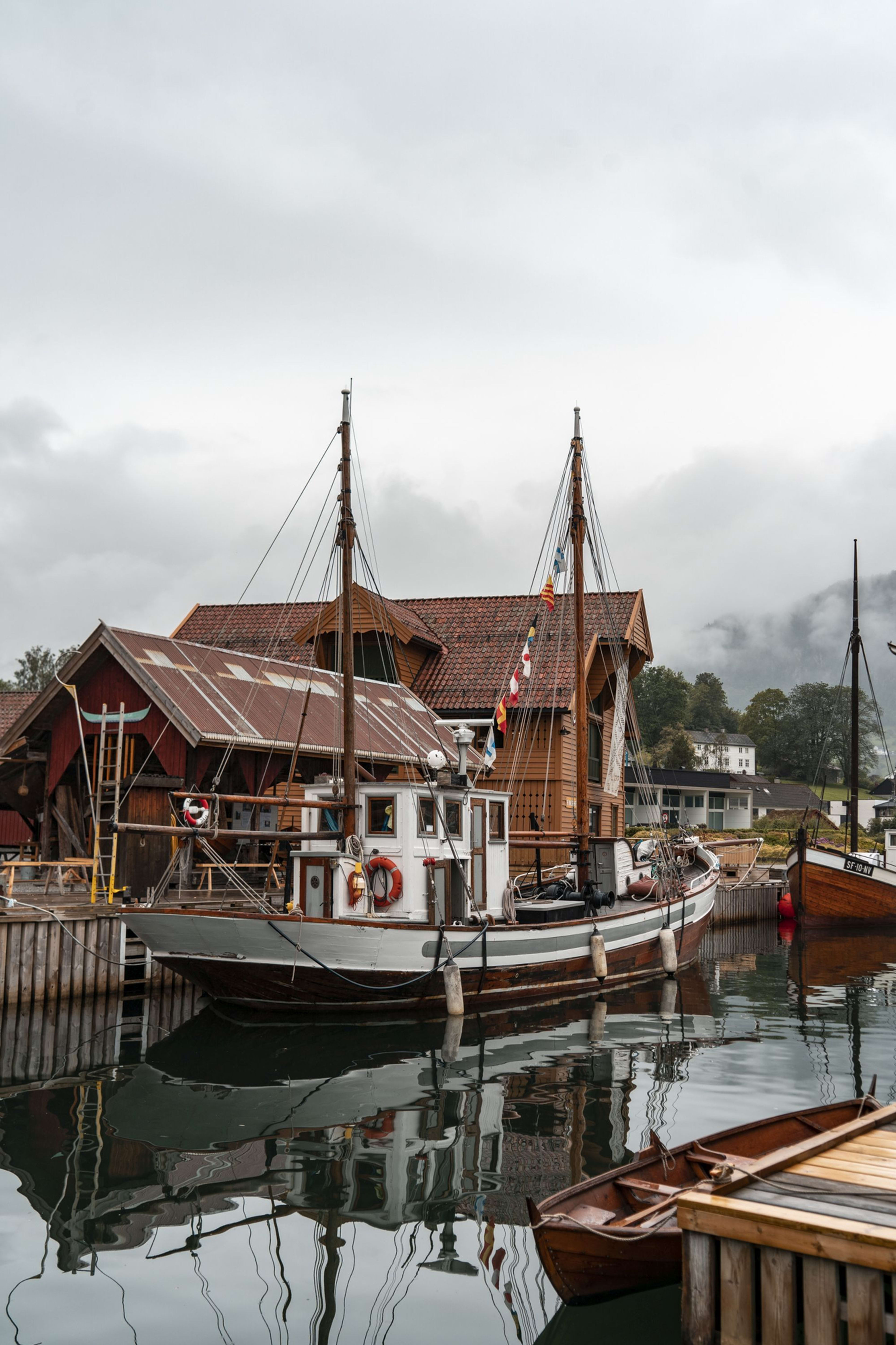 Holzboote an Bootshäusern mit Wald und Nebel im Hintergrund.