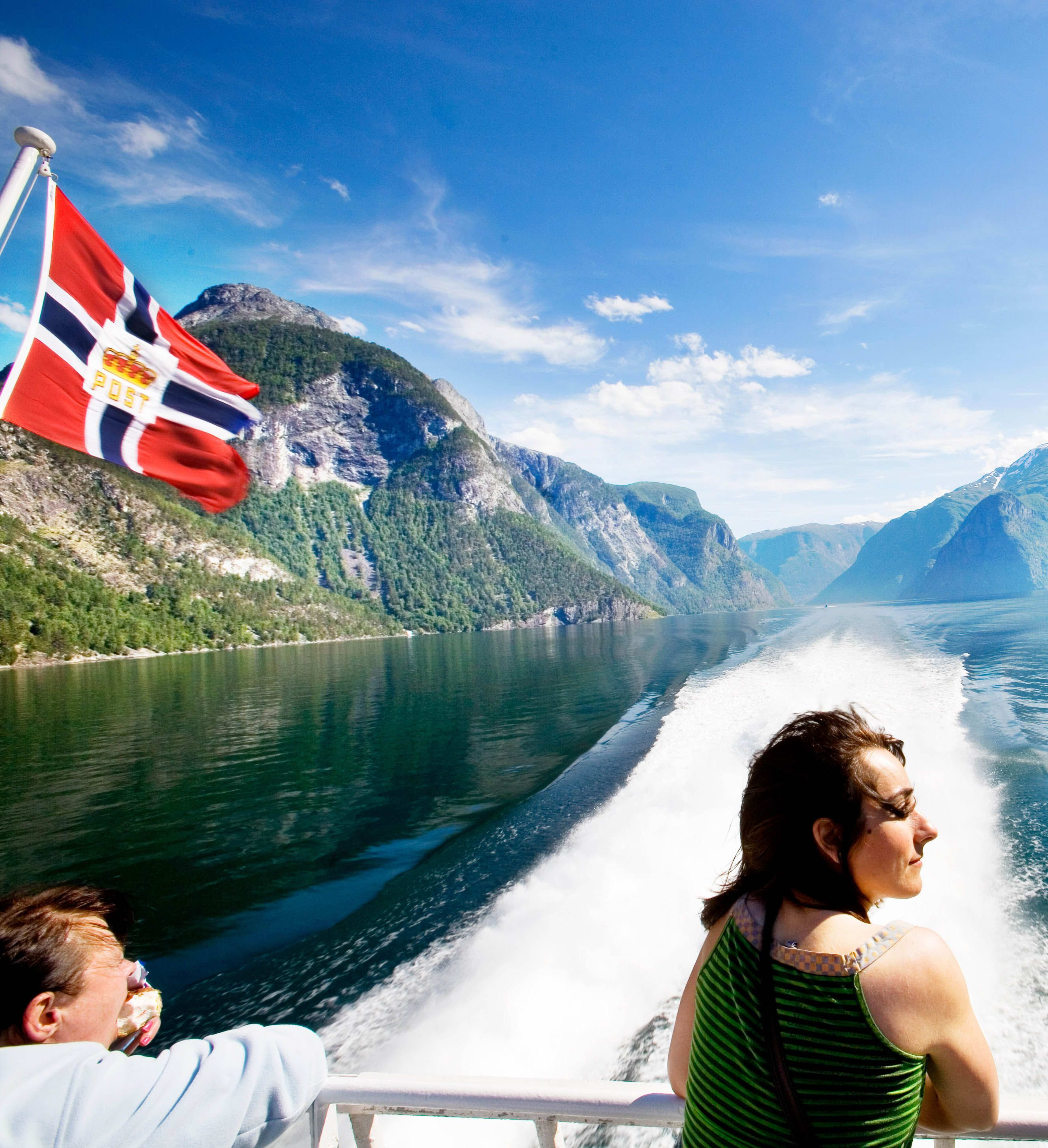 Boot am Sognefjord mit wehender Flagge und Kielwasser.