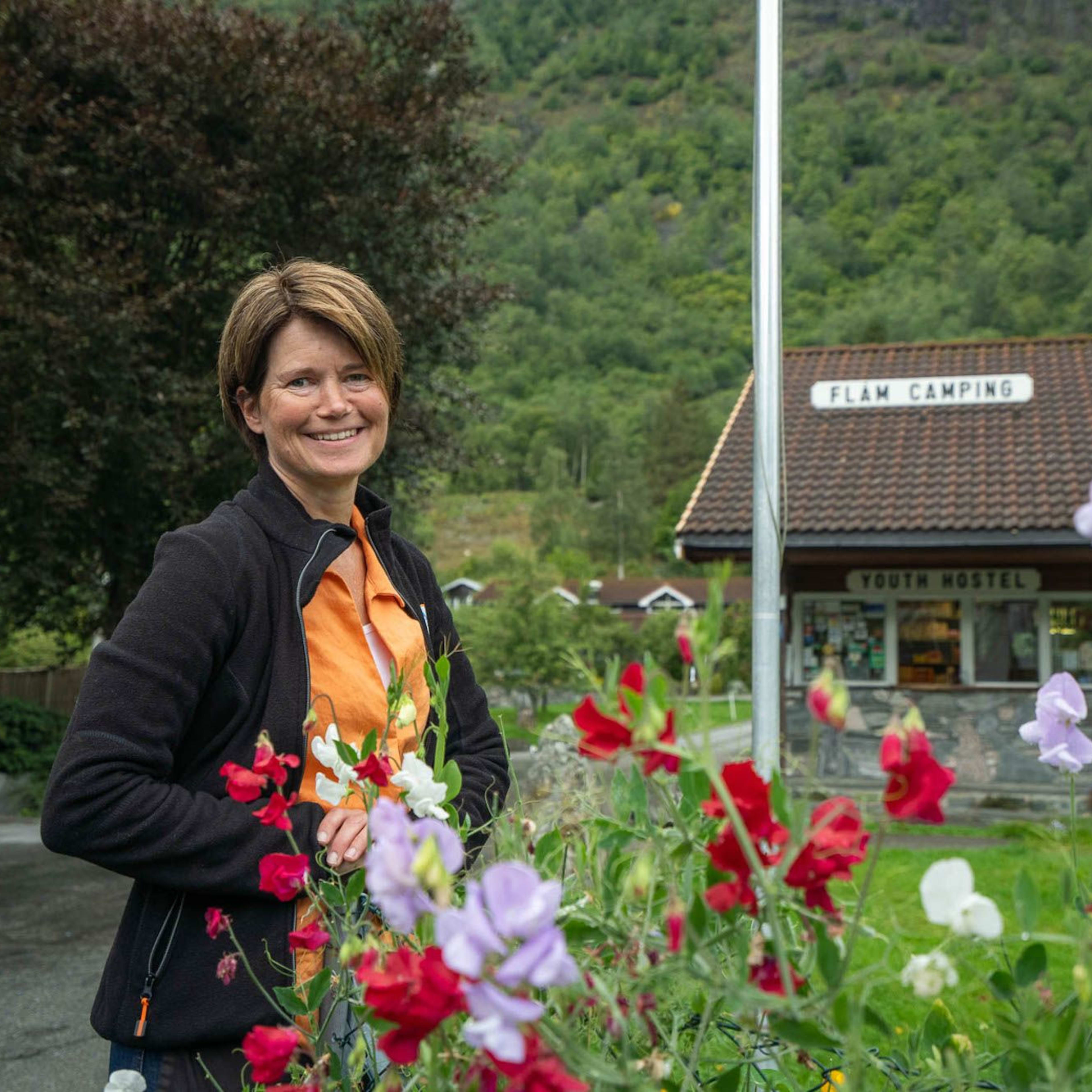 Hostess at Flåm camping welcomes everyone and is arranging fresh flowers on the tables.
