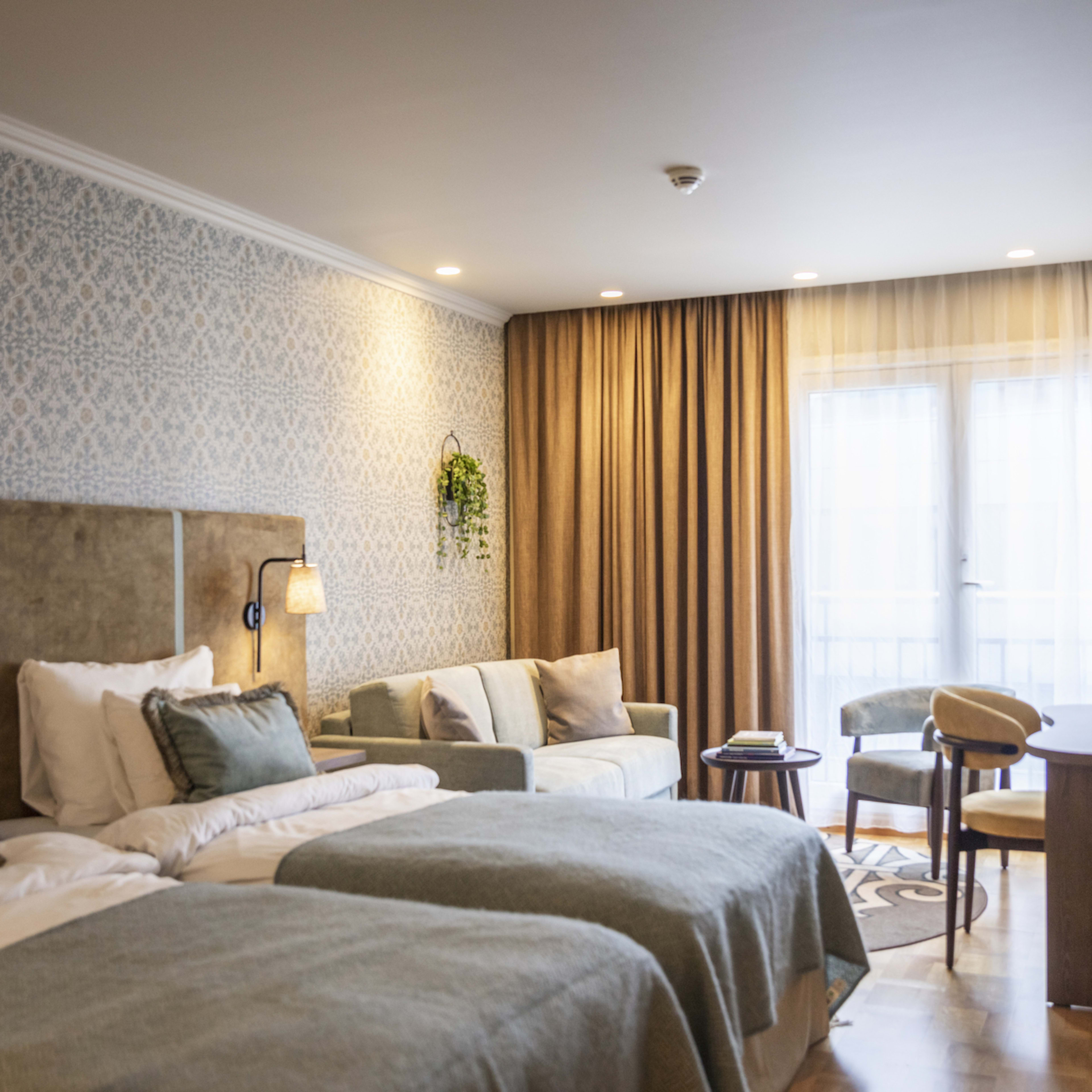 Superior Zimmer mit zwei Einzelbetten, Sofa, Sessel und kleinem Tisch mit Blick auf Bergens Stadtzentrum