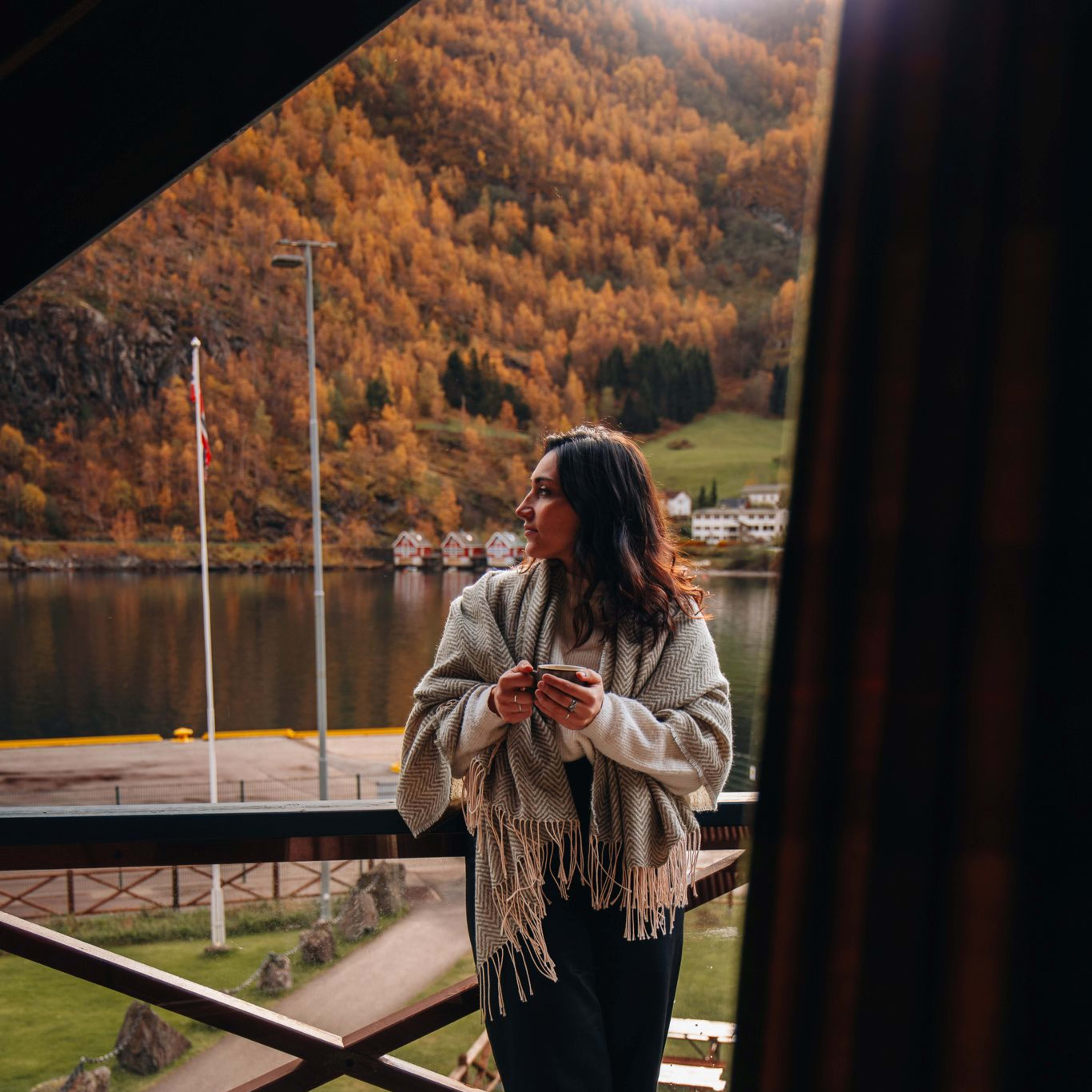 Guest relaxing on the balcony at Flåmsbrygga Hotel in Flåm with fjord views