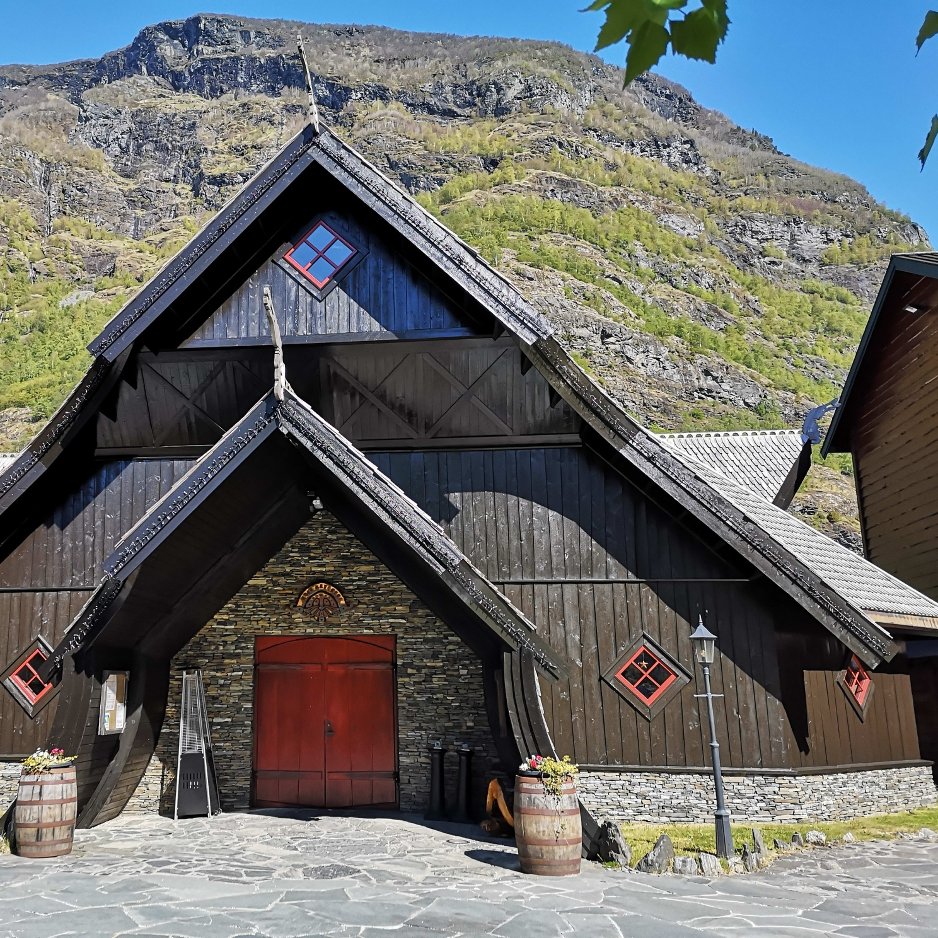 Ægir Gastropubs karakteristiske vikingstil-fasade i Flåm en solrik sommerdag med fjell i bakgrunnen (9