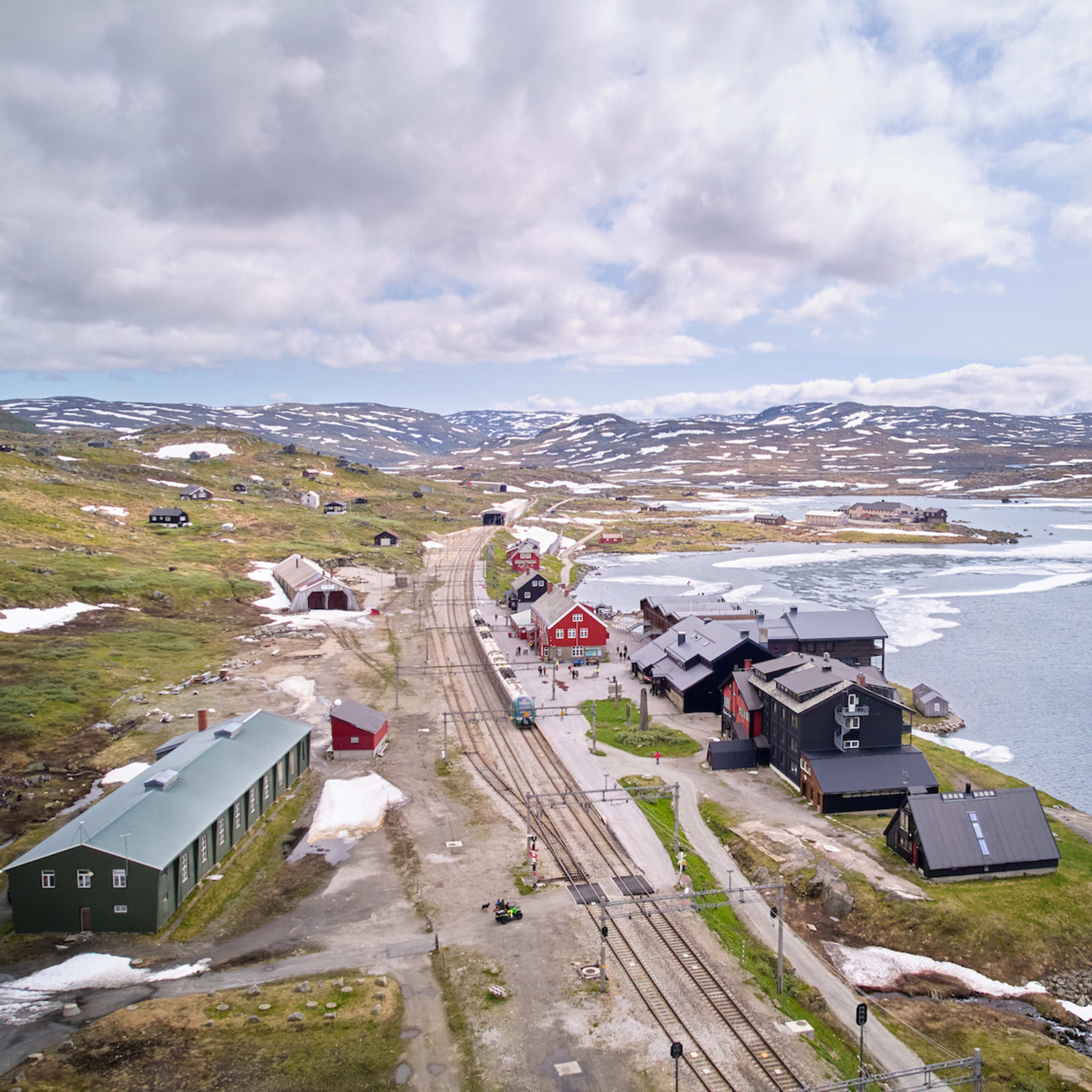 Luftaufnahme Finse Bahnhof mit Hotel Finse 1222 umgeben von Gletscherwasser und norwegischer Berglandschaft