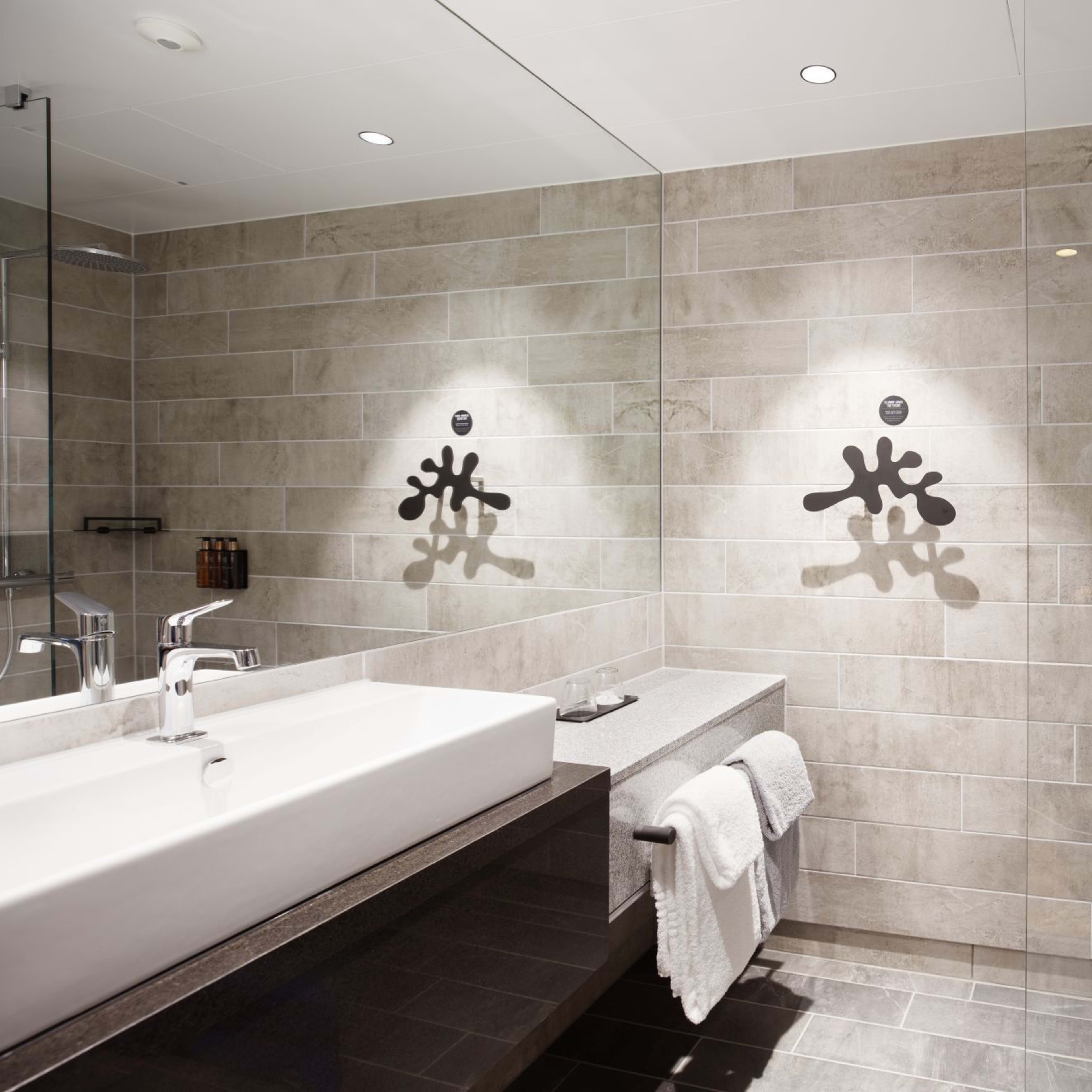 Elegantes Badezimmer im Clarion Hotel The Hub Oslo mit zeitgenössischem beigem Design und Premium-Ausstattung