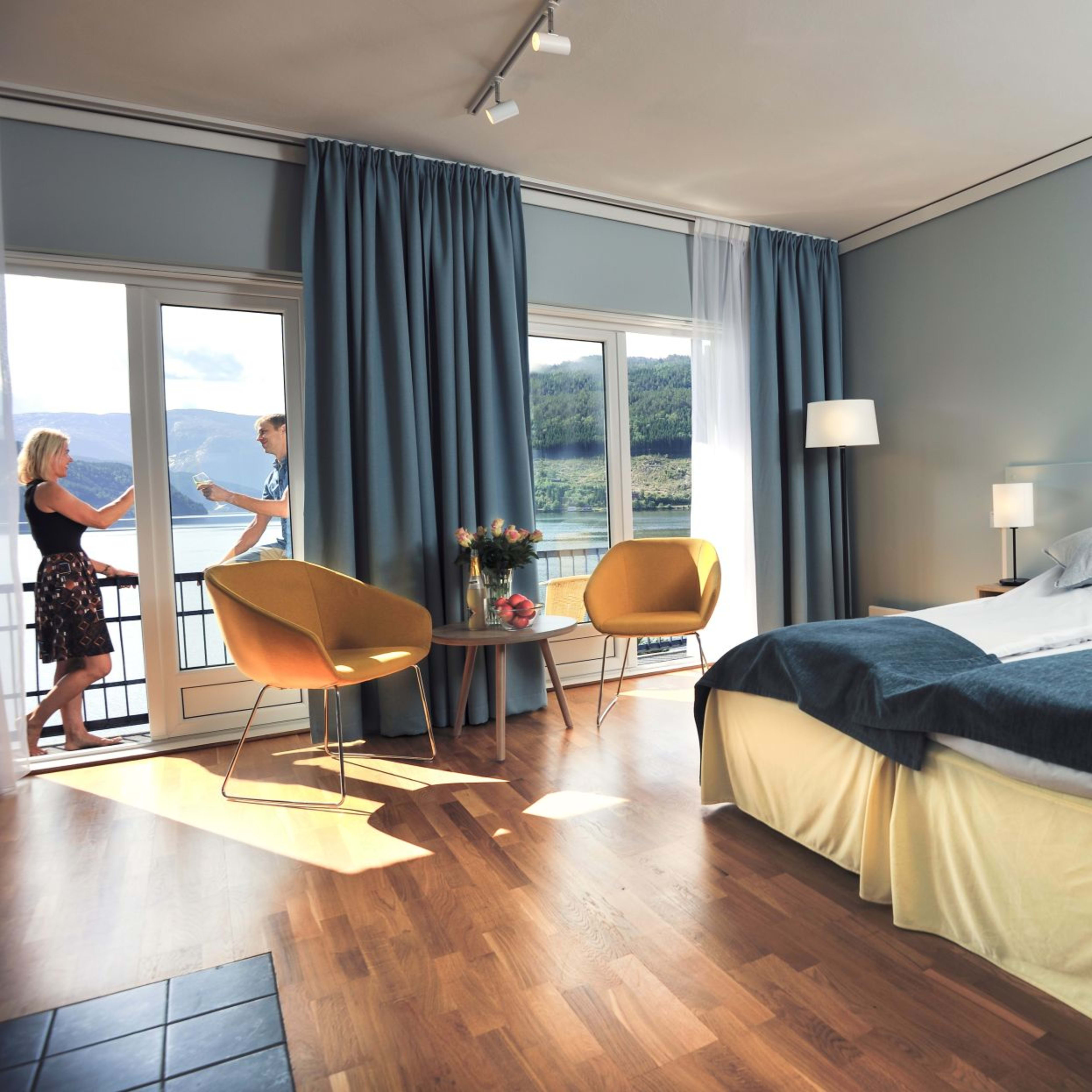 Modern double room at Brakanes Hotel Ulvik with fjord view balcony and couple enjoying drinks
