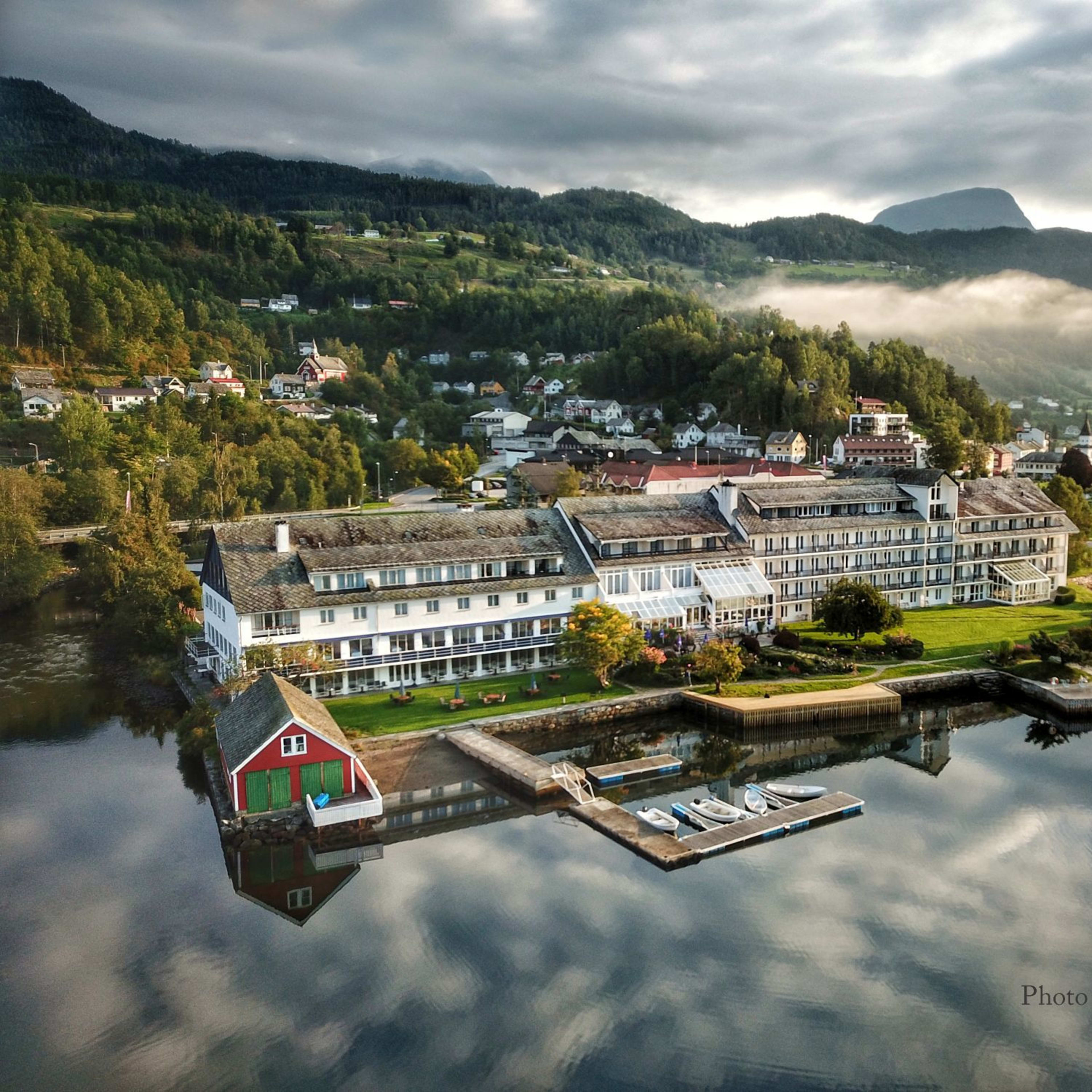 Aerial view of Brakanes Hotel in Ulvik surrounded by dramatic Norwegian mountains and pristine fjord waters