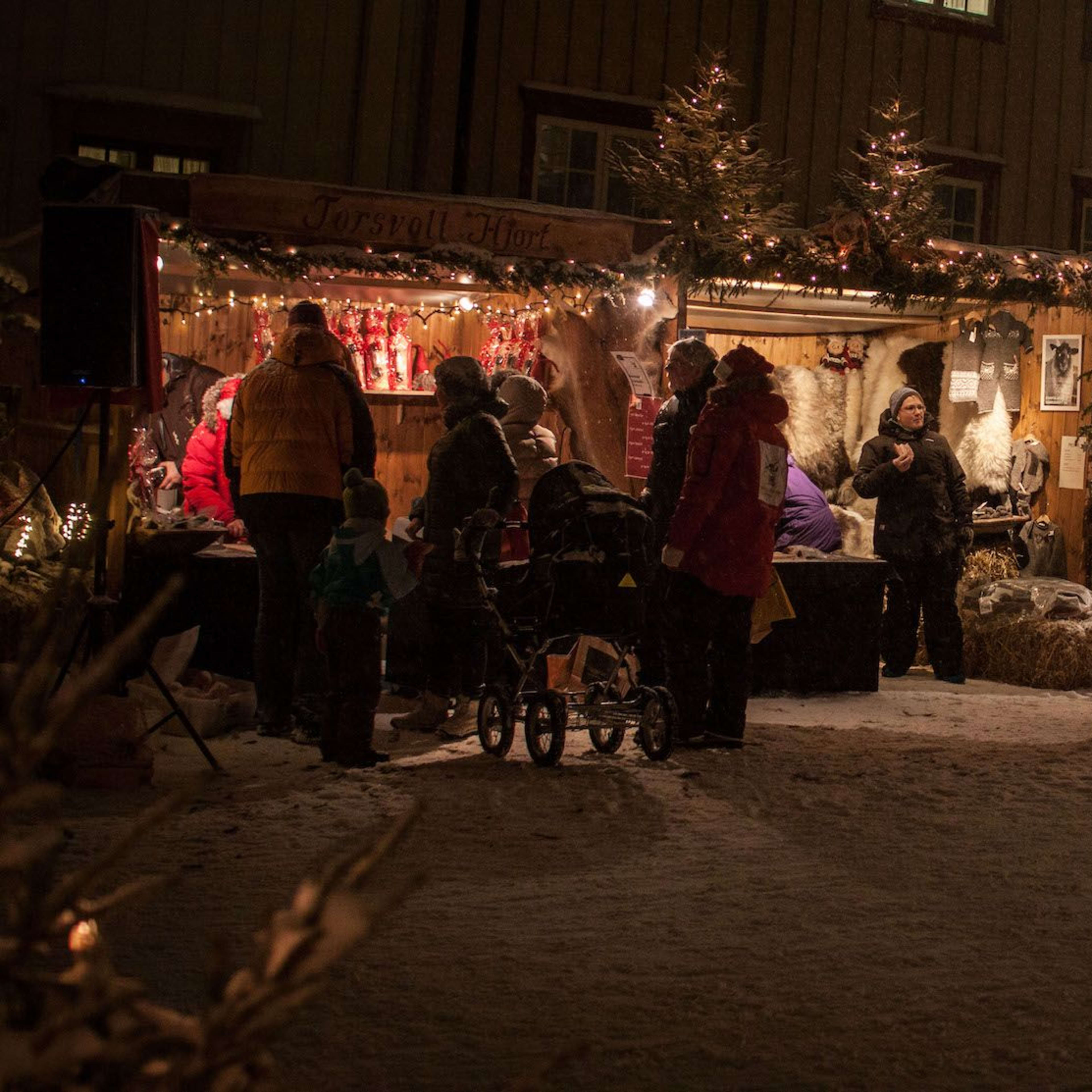 A cozy outdoor Christmas market at night with stalls selling handcrafted goods, decorations, and winter items.
