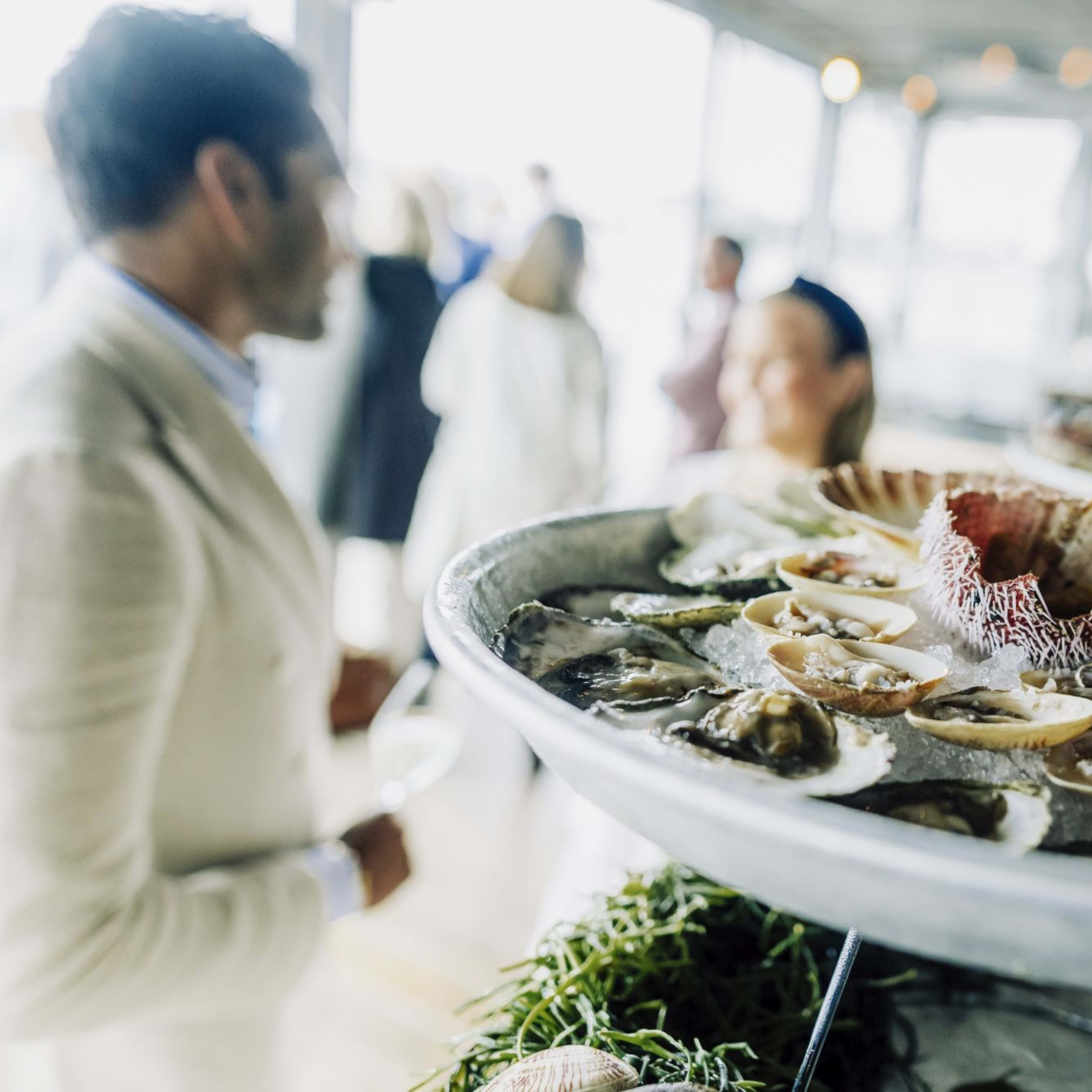 Fresh seafood platter with oysters, clams, and sea urchin on ice, served elegantly at sophisticated indoor event.