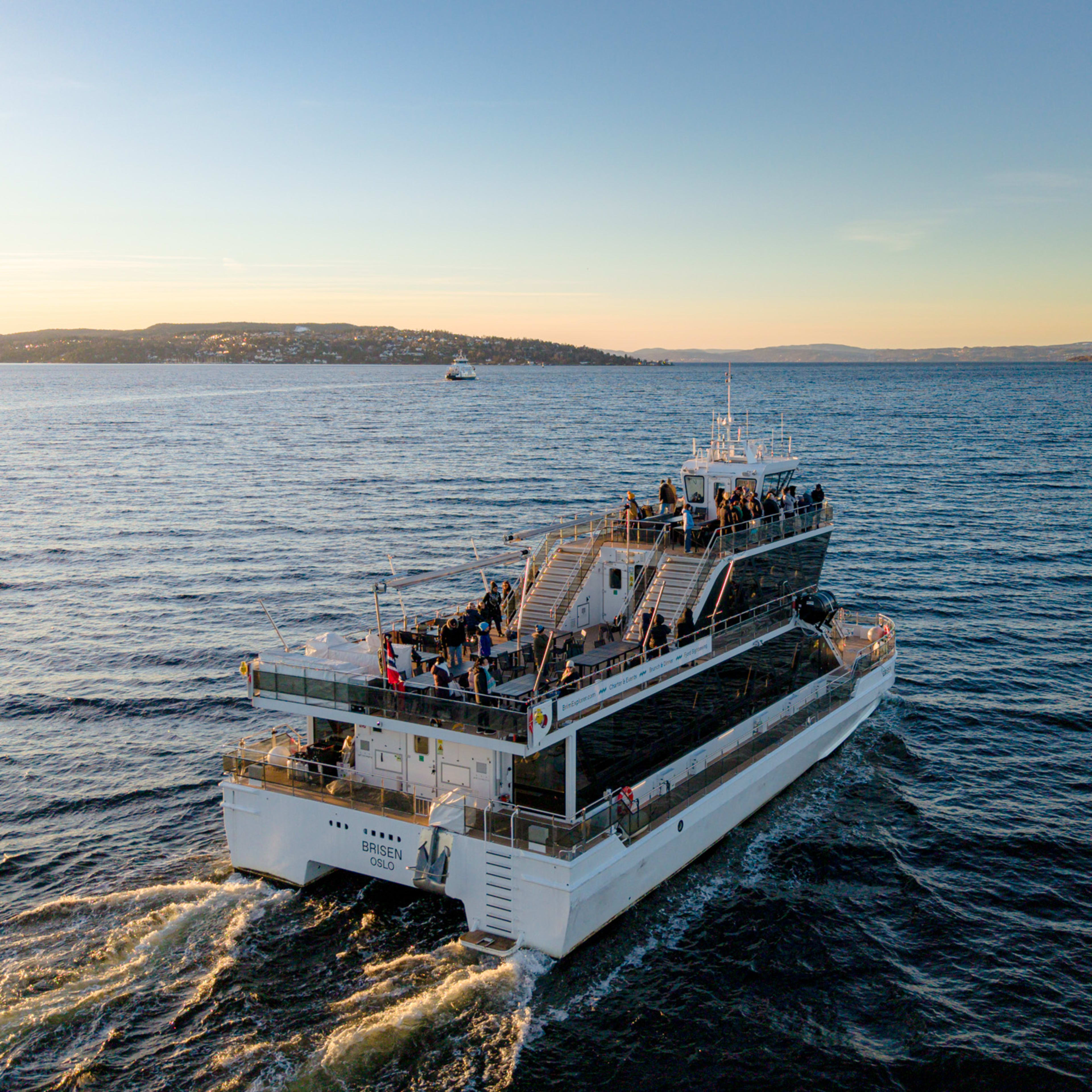 White cruise vessel with guests on deck in Oslo fjord