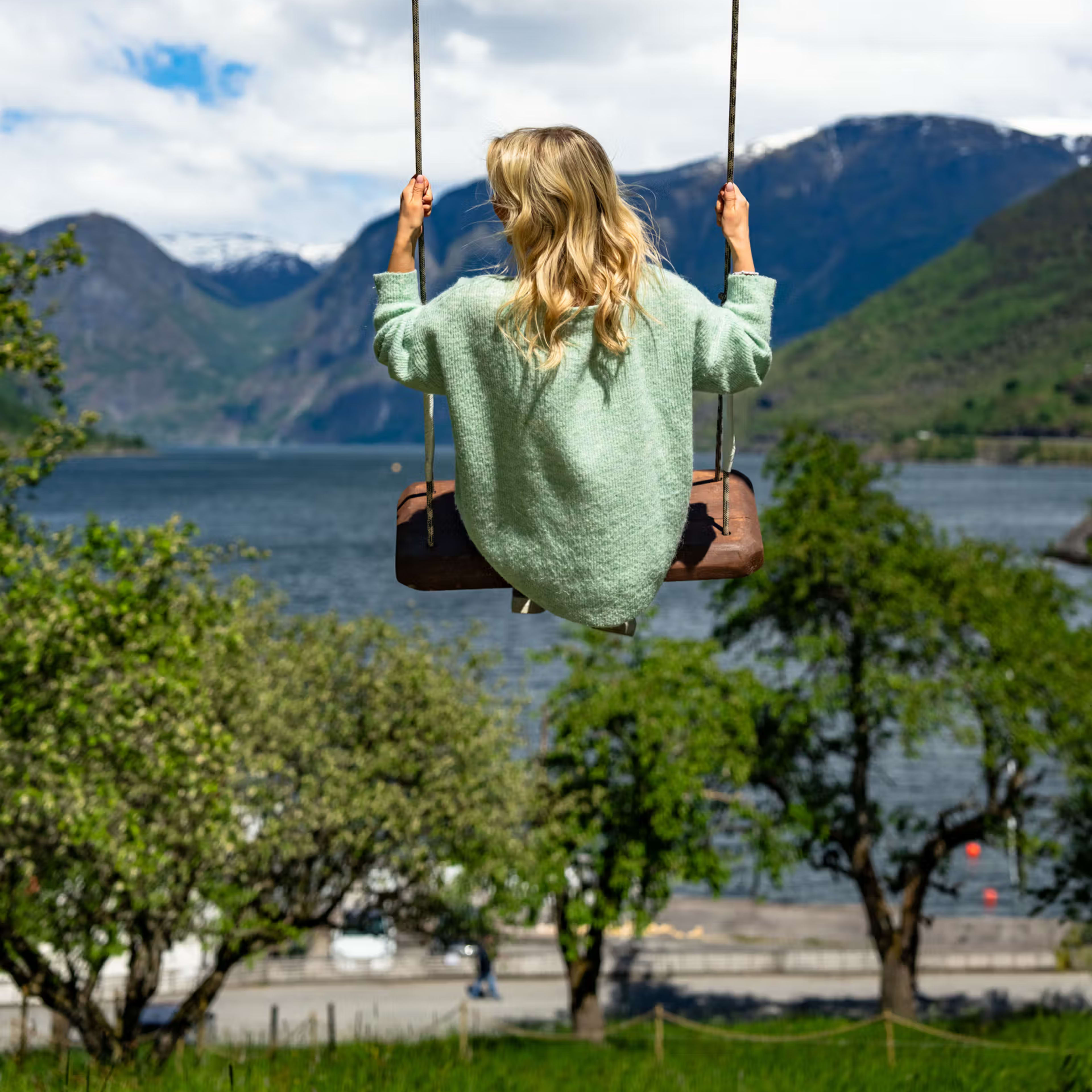 Tourist enjoying scenic swing photo opportunity at Flåm fjord farm