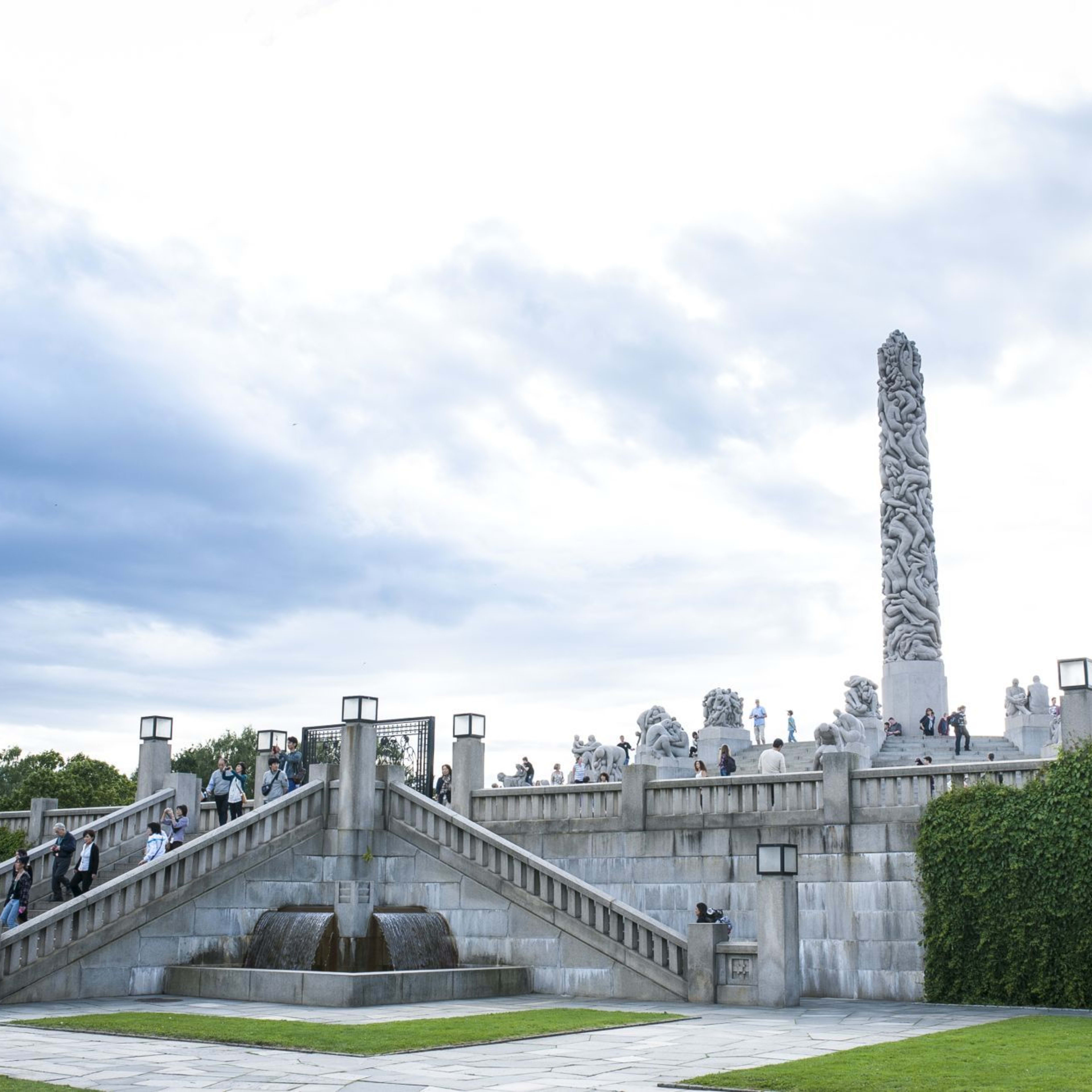 Vigeland-Skulpturenpark mit großer Treppe, Skulpturen und Besuchern, die die Kunst unter teils bewölktem Himmel bewundern.