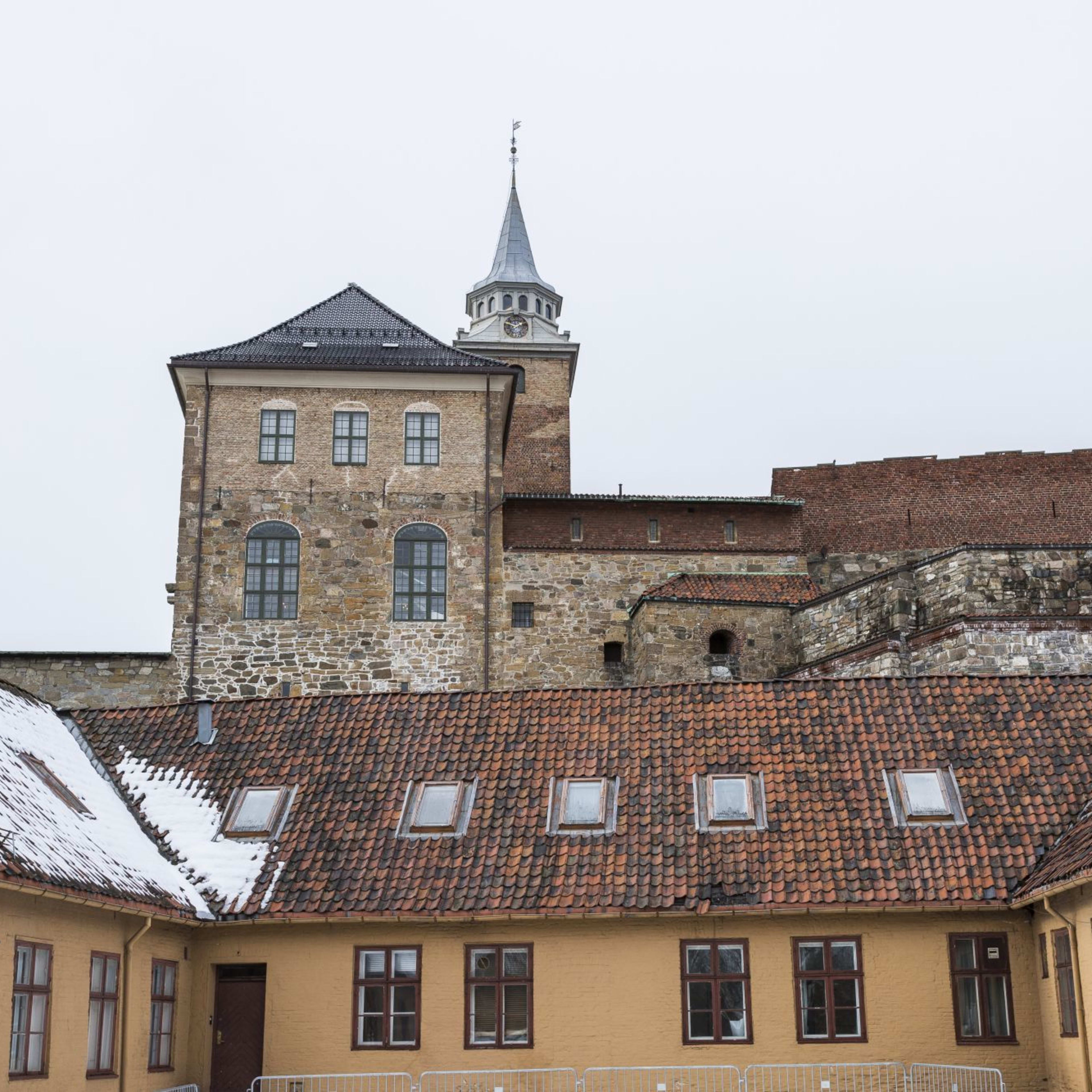 Historische Steinburg mit hohen Türmen, Backsteinmauern und Dächern, die teilweise mit Schnee bedeckt sind, unter grauem Himmel.