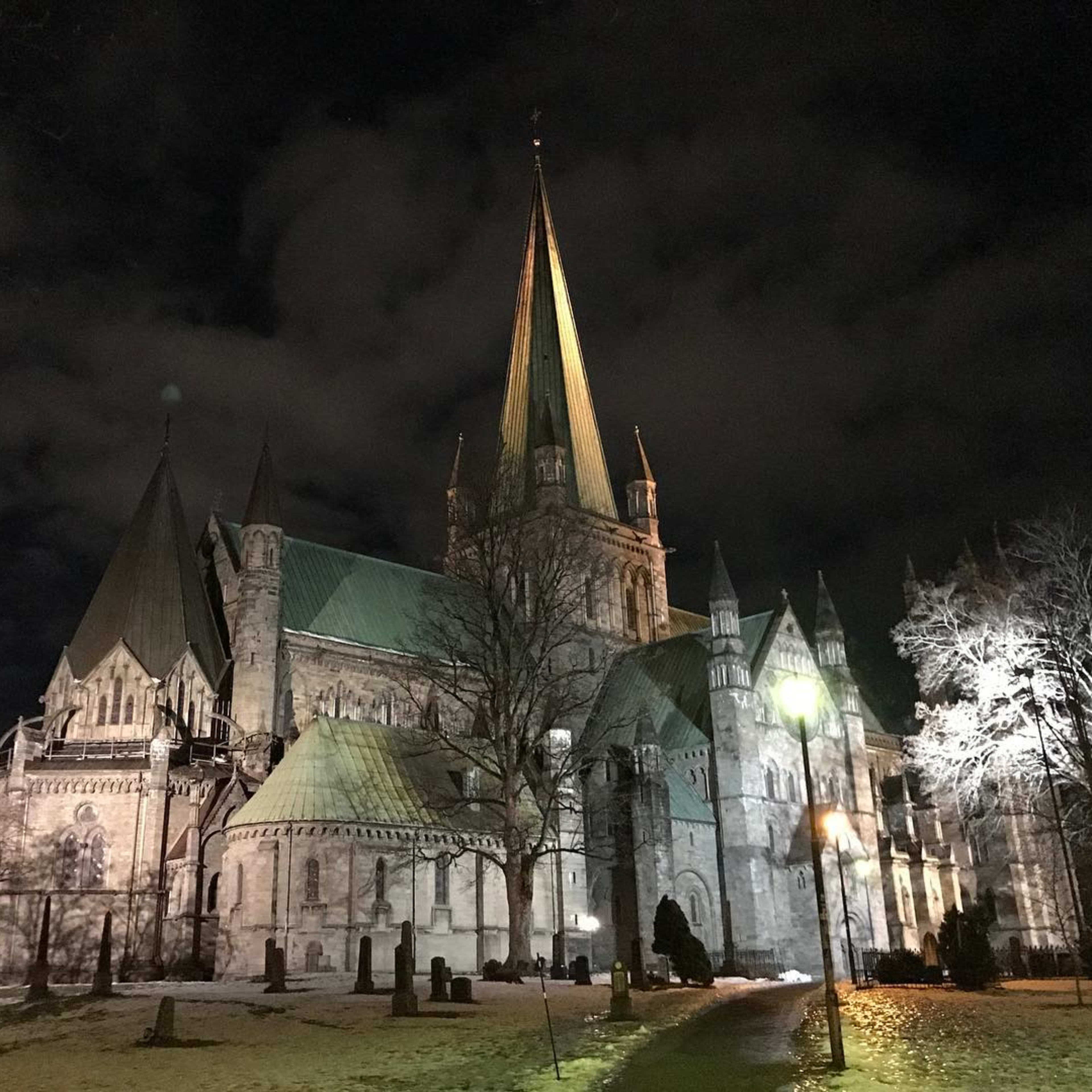 Opplyst katedral med grønne spir lyser opp snølagt nattelandskap.