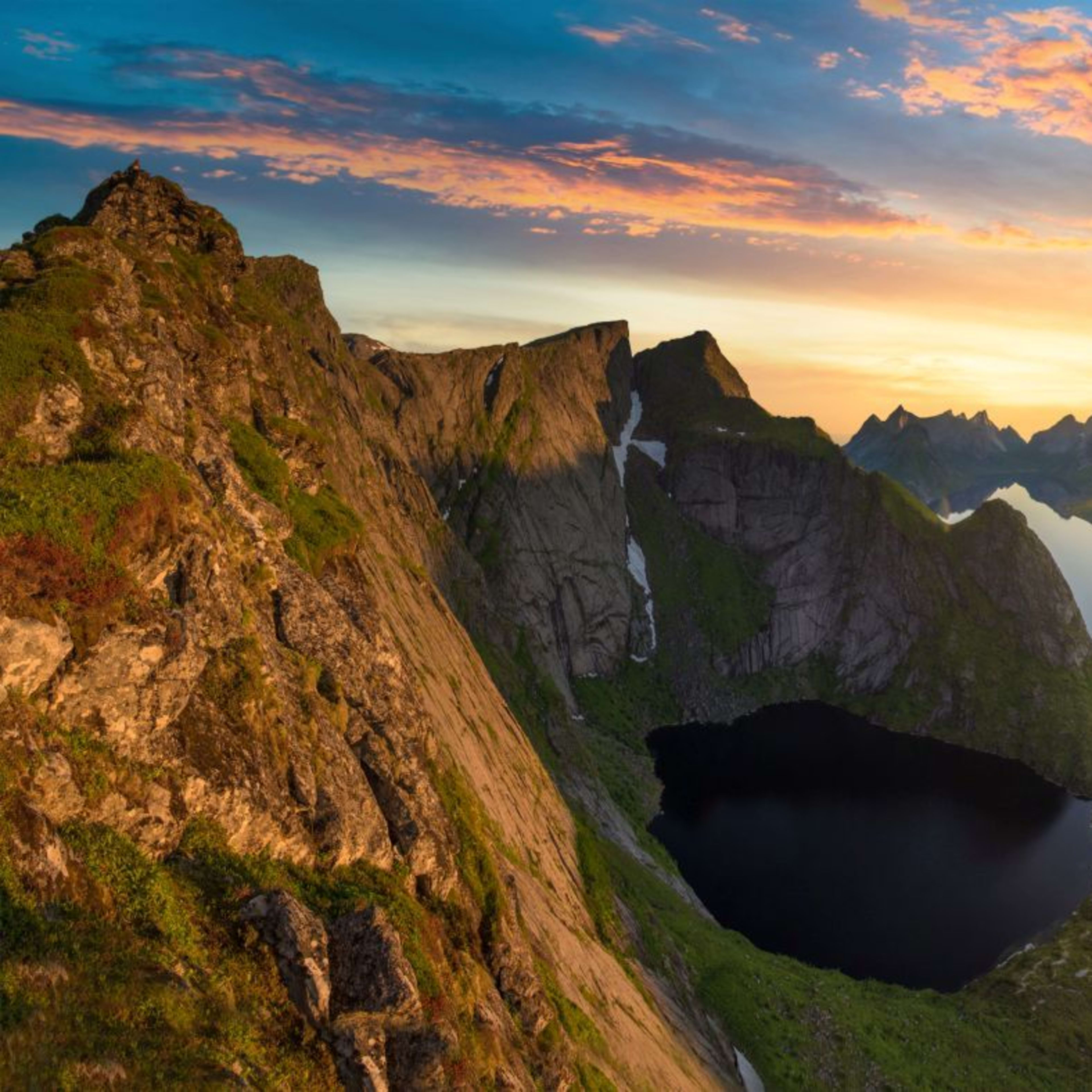 Turgåer på fjellhylle i solnedgang med utsikt over fjorder og øyer.